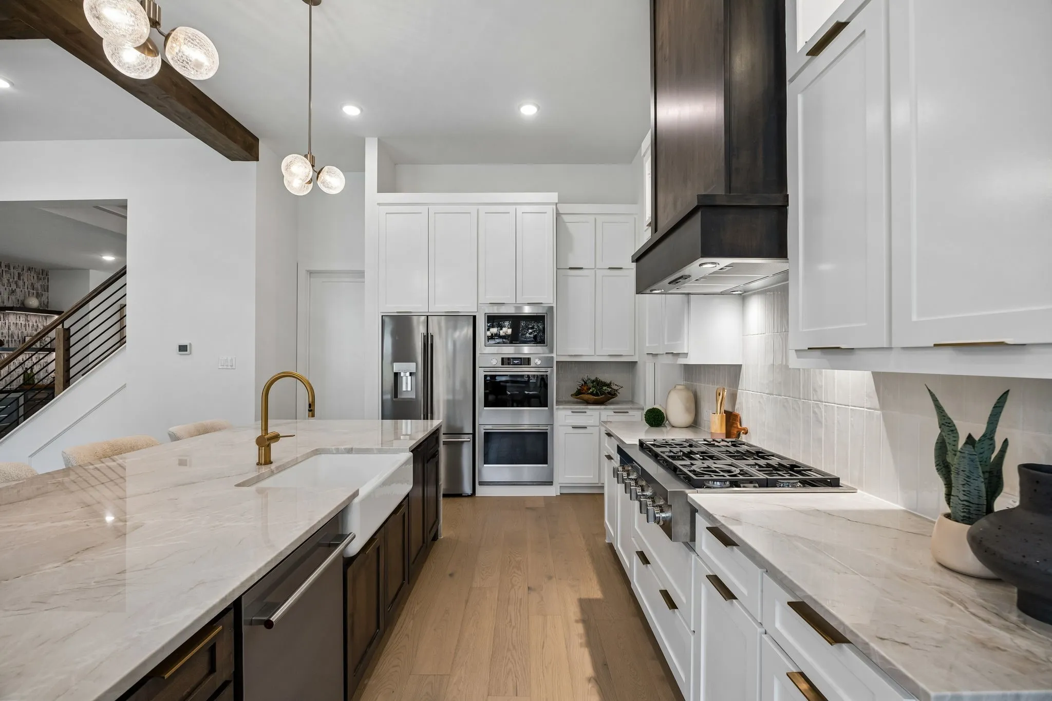 Gourmet kitchen featuring a large island, farm sink, gas range, double ovens, and wood-finish flooring
