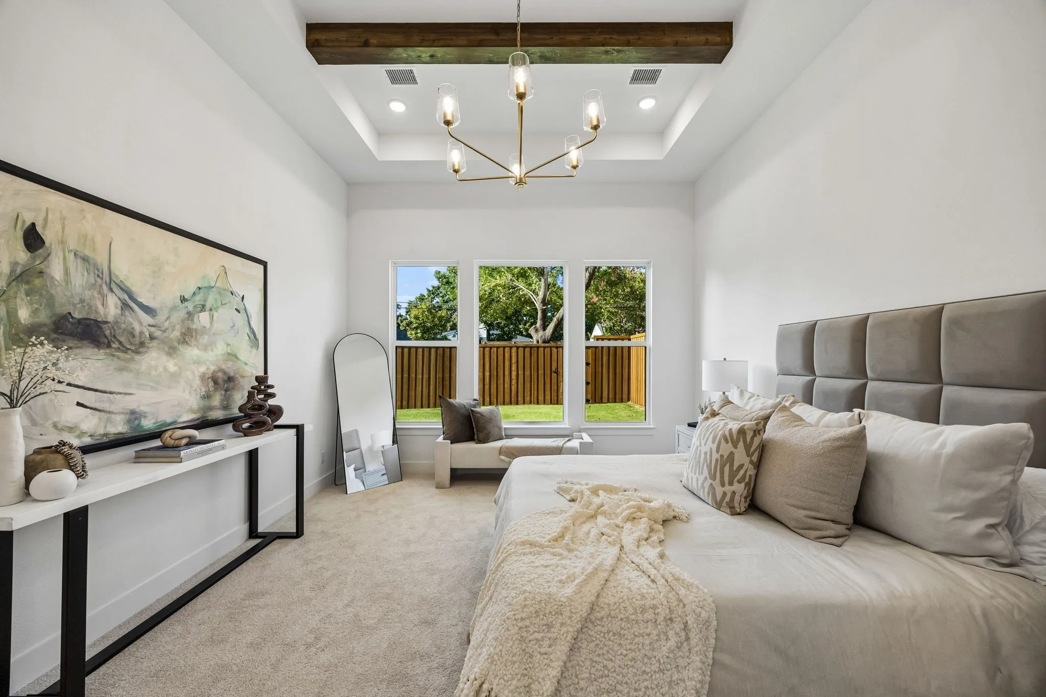 Tray ceiling with a decorative wood beam and a contemporary chandelier