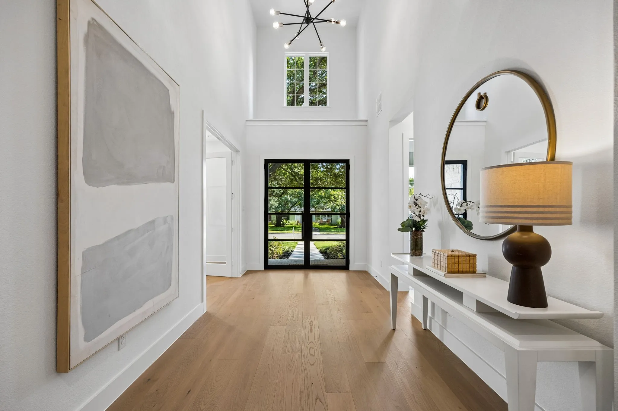 Vaulted entry with wood-finish flooring, a modern chandelier, and a black-framed glass entry door