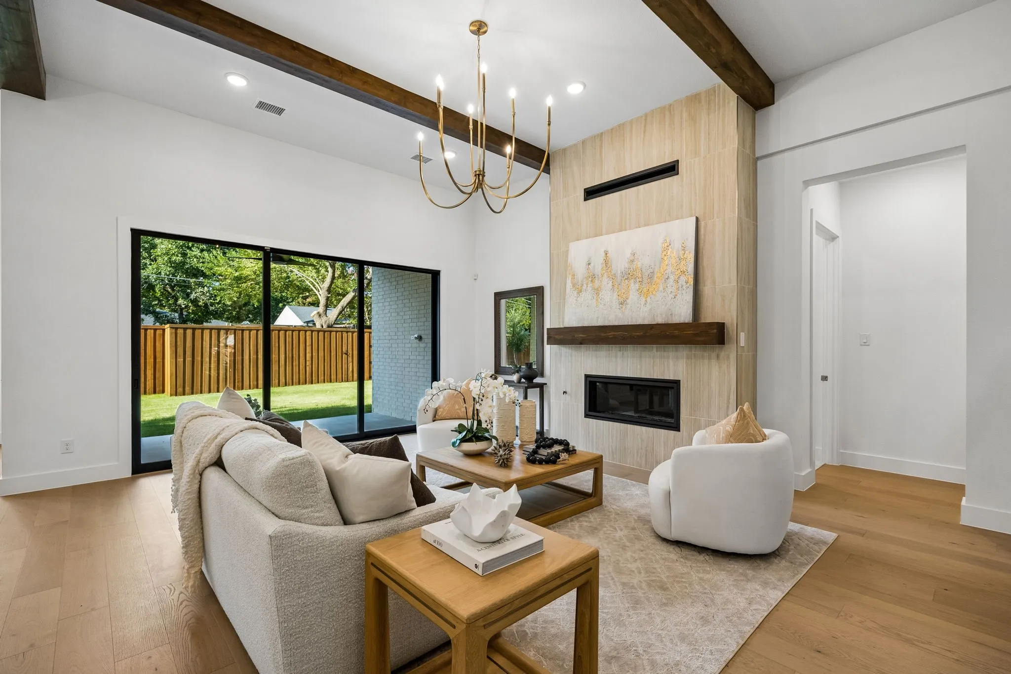 Vaulted ceiling with exposed wood beams, a modern fireplace with a wood-finish mantel and tile surround, recessed lighting, and wood-finish flooring