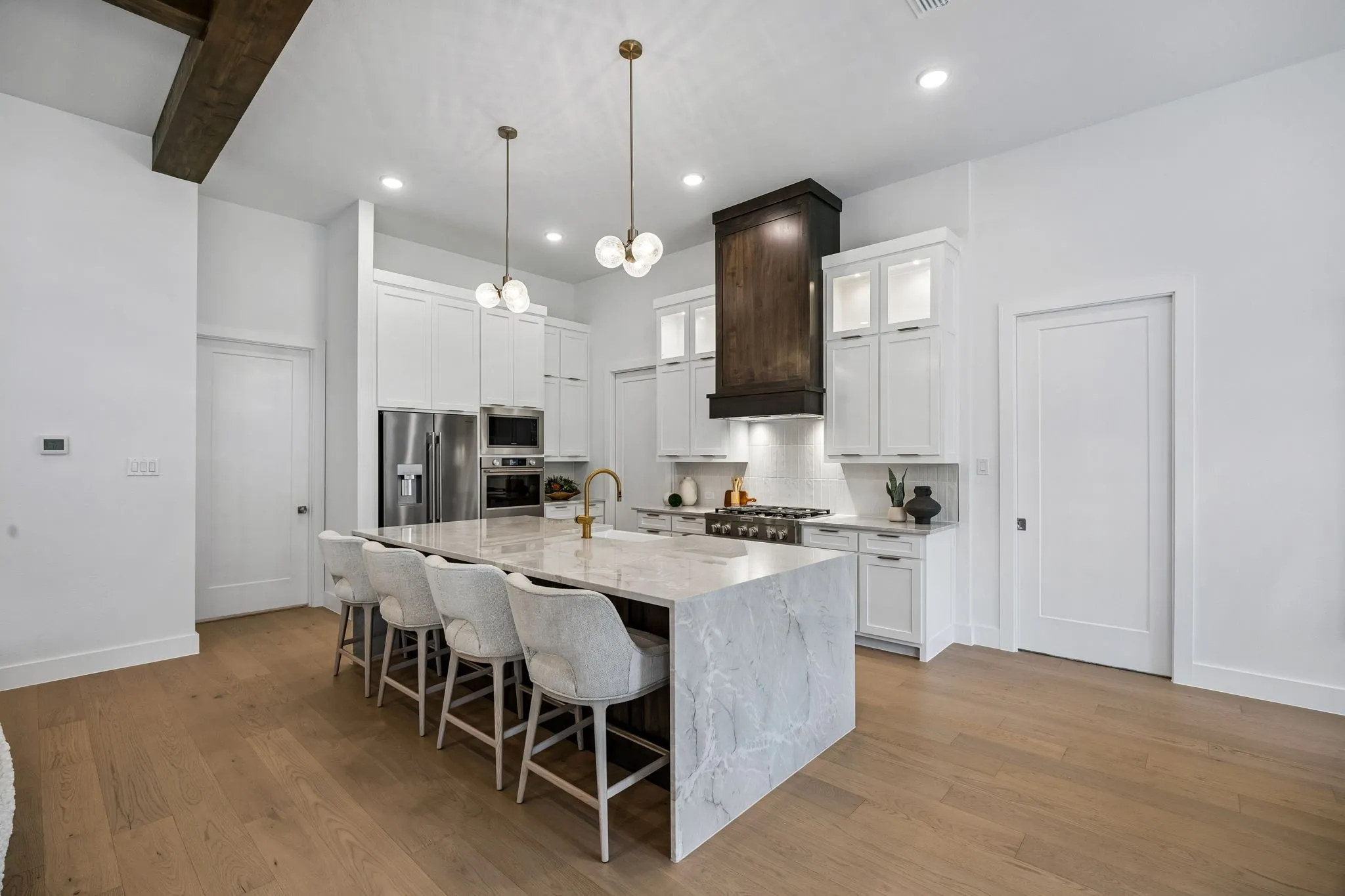 Spacious kitchen featuring a large waterfall island, stainless steel appliances, recessed lighting, and wood-finish flooring