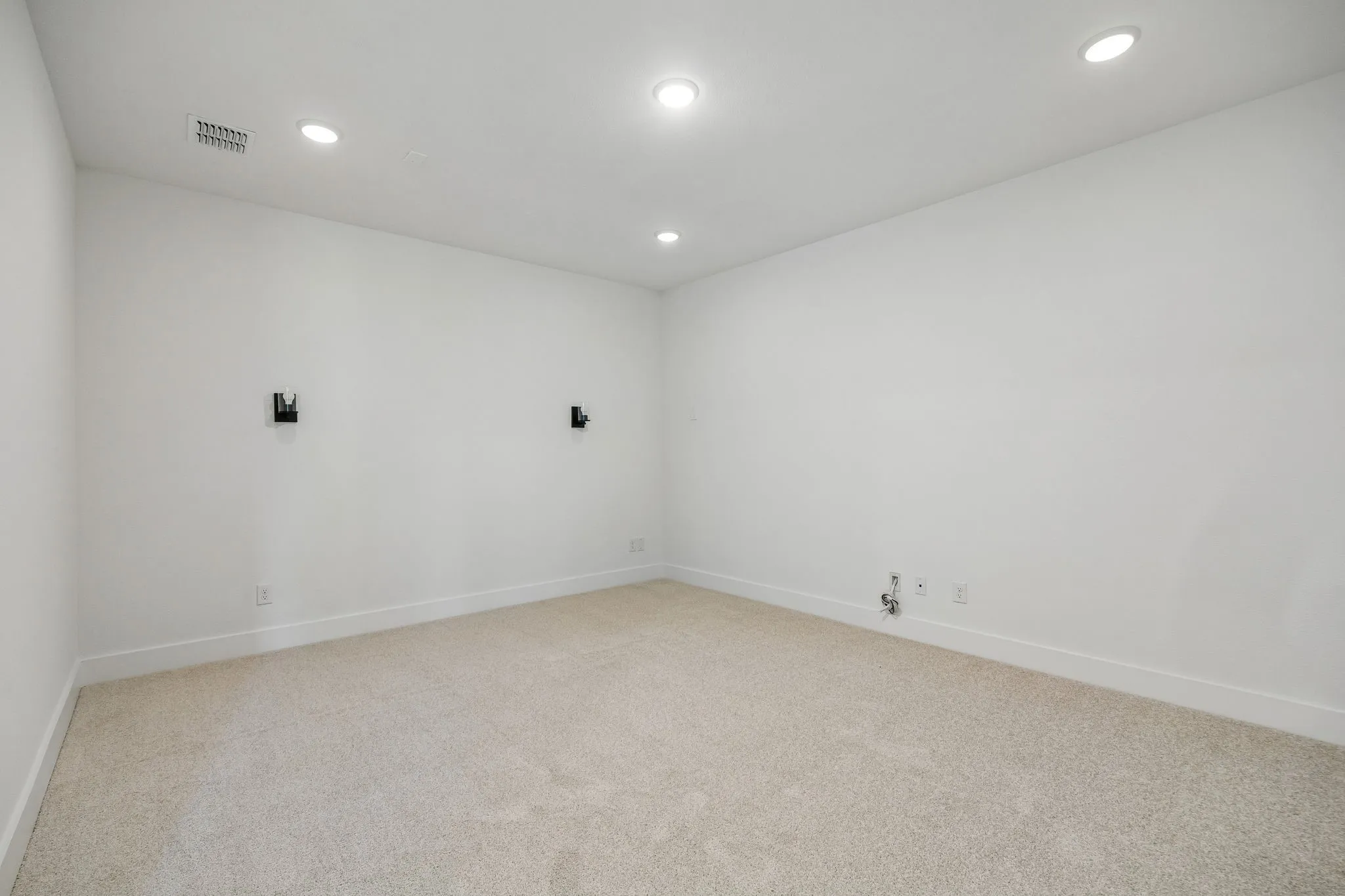 Recessed ceiling lighting illuminates the carpeted flooring and neutral wall finishes