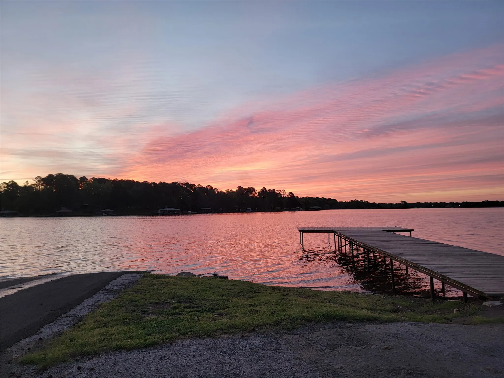 Private lake access featuring a wooden dock and boat launch