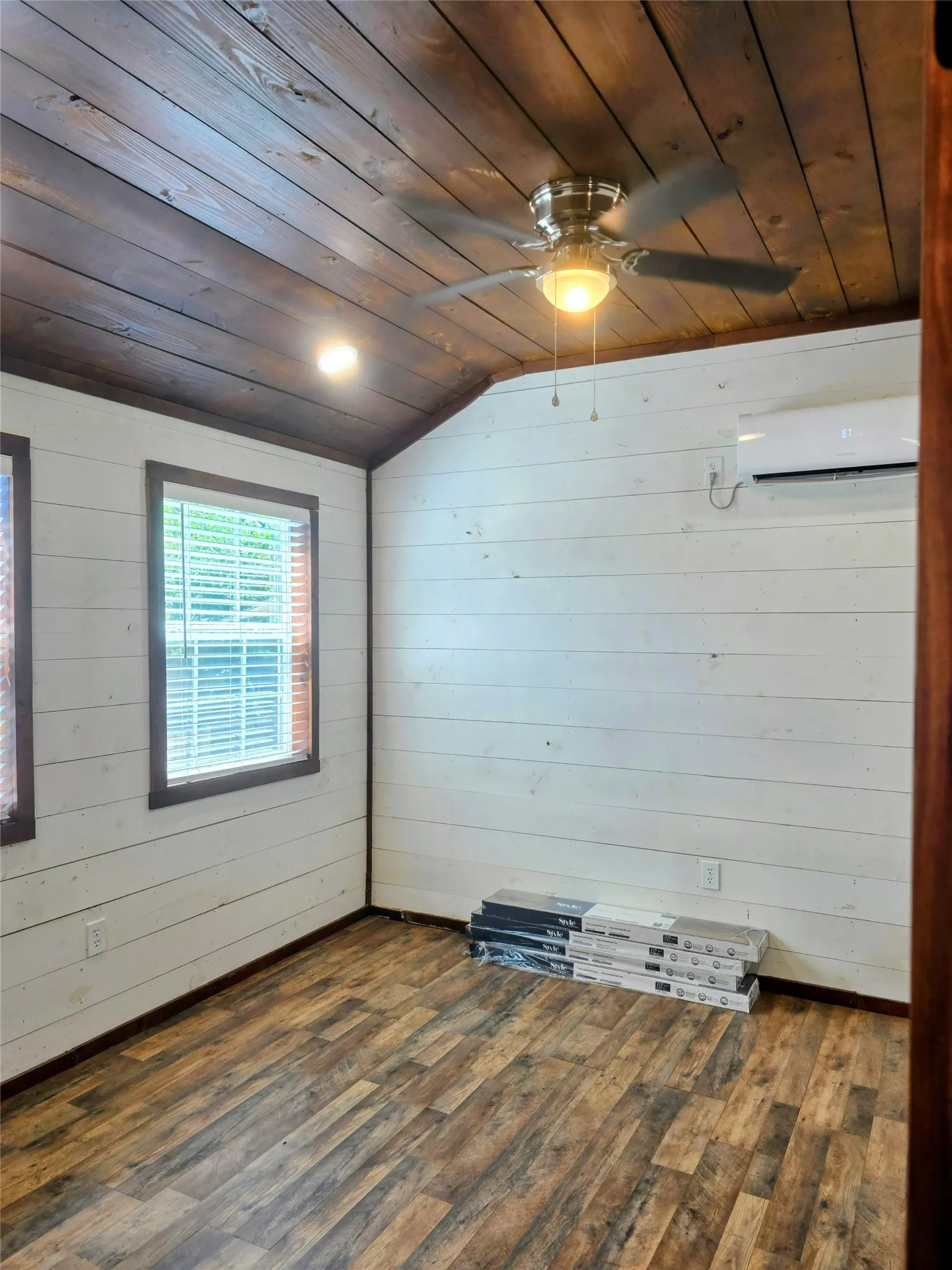 Room featuring wood-finish flooring, white shiplap walls, and a vaulted wood-plank ceiling