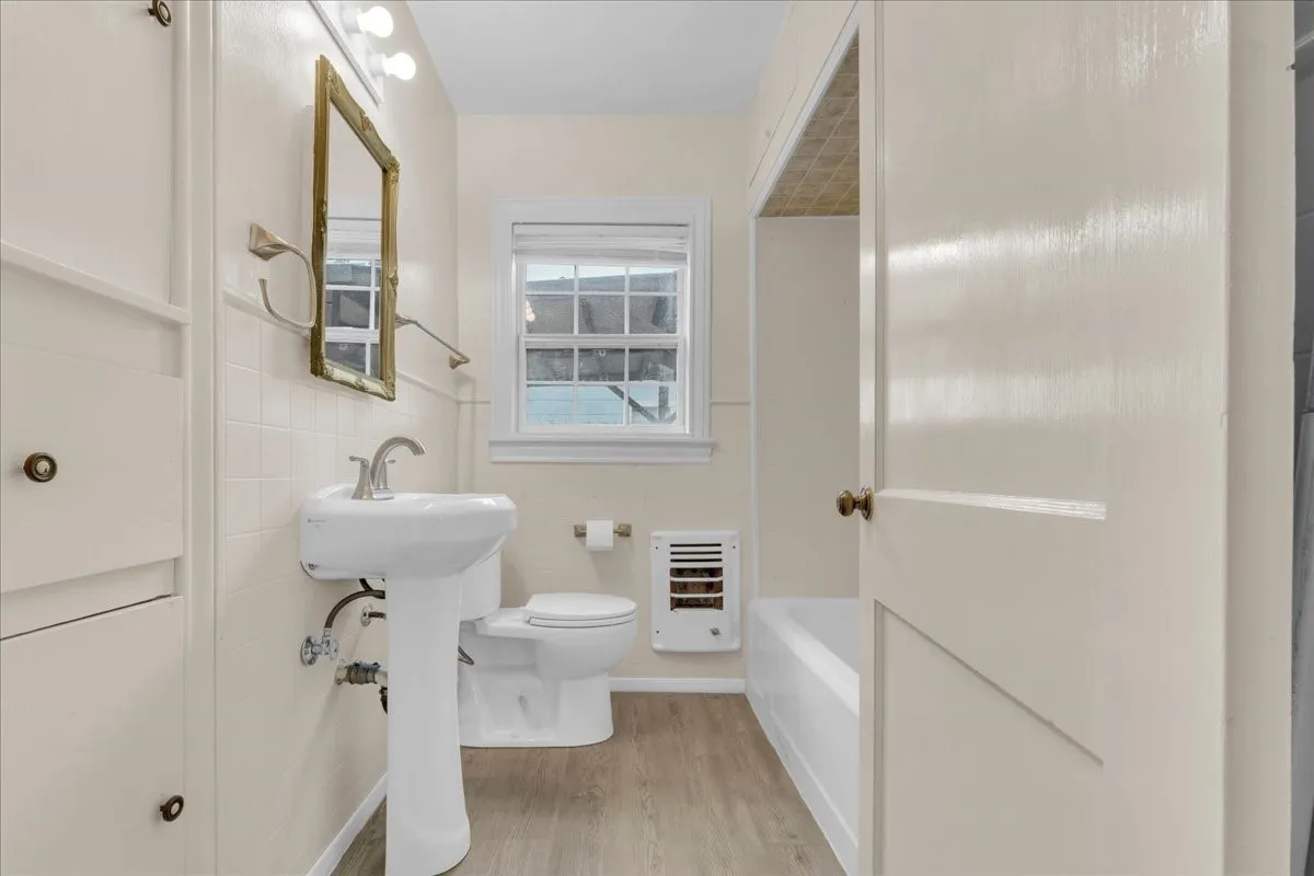 Bathroom featuring a pedestal sink, a window, built-in cabinetry, a toilet, and a bathtub