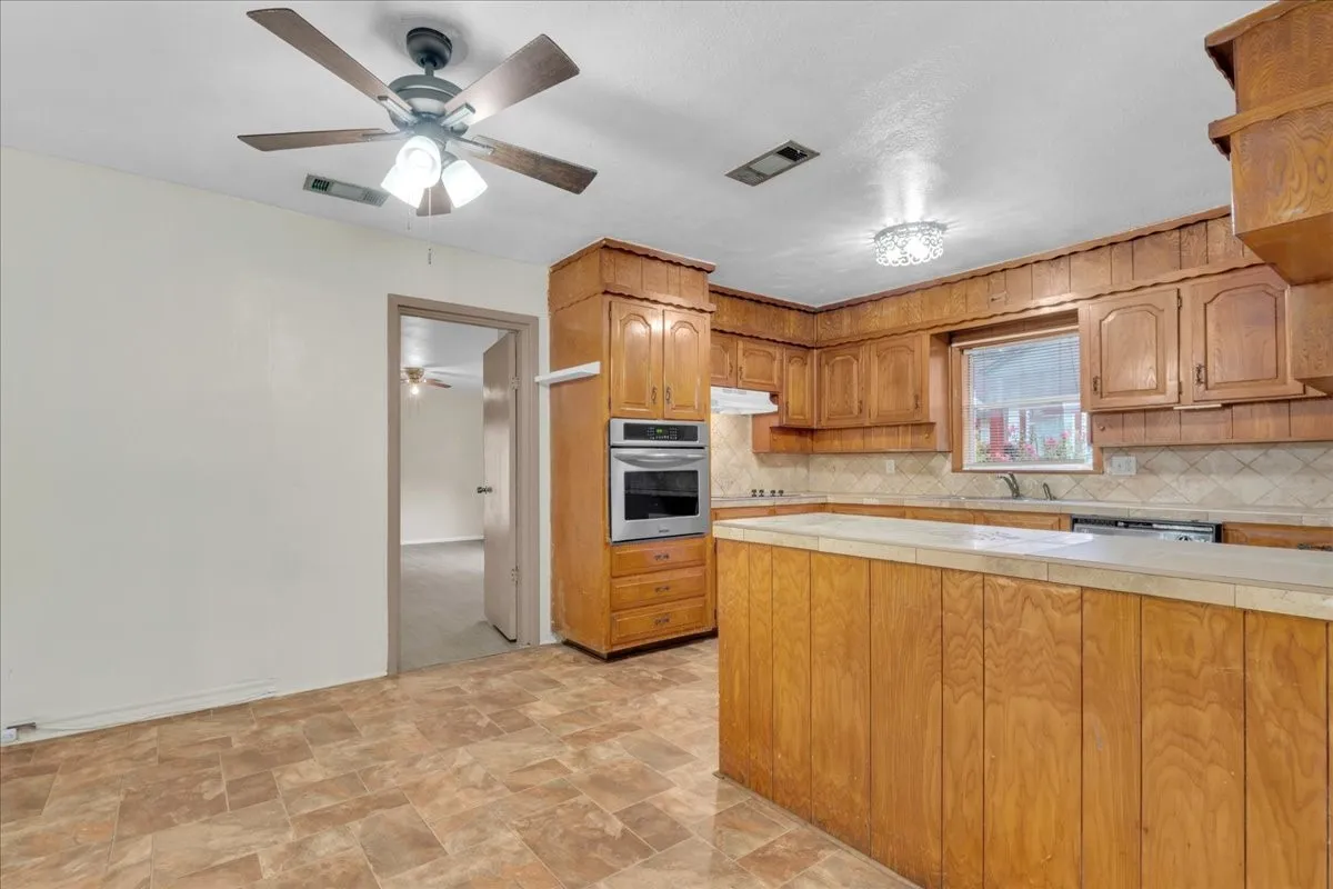 Kitchen featuring wood-panel cabinetry, light-toned countertops, and a built-in double oven