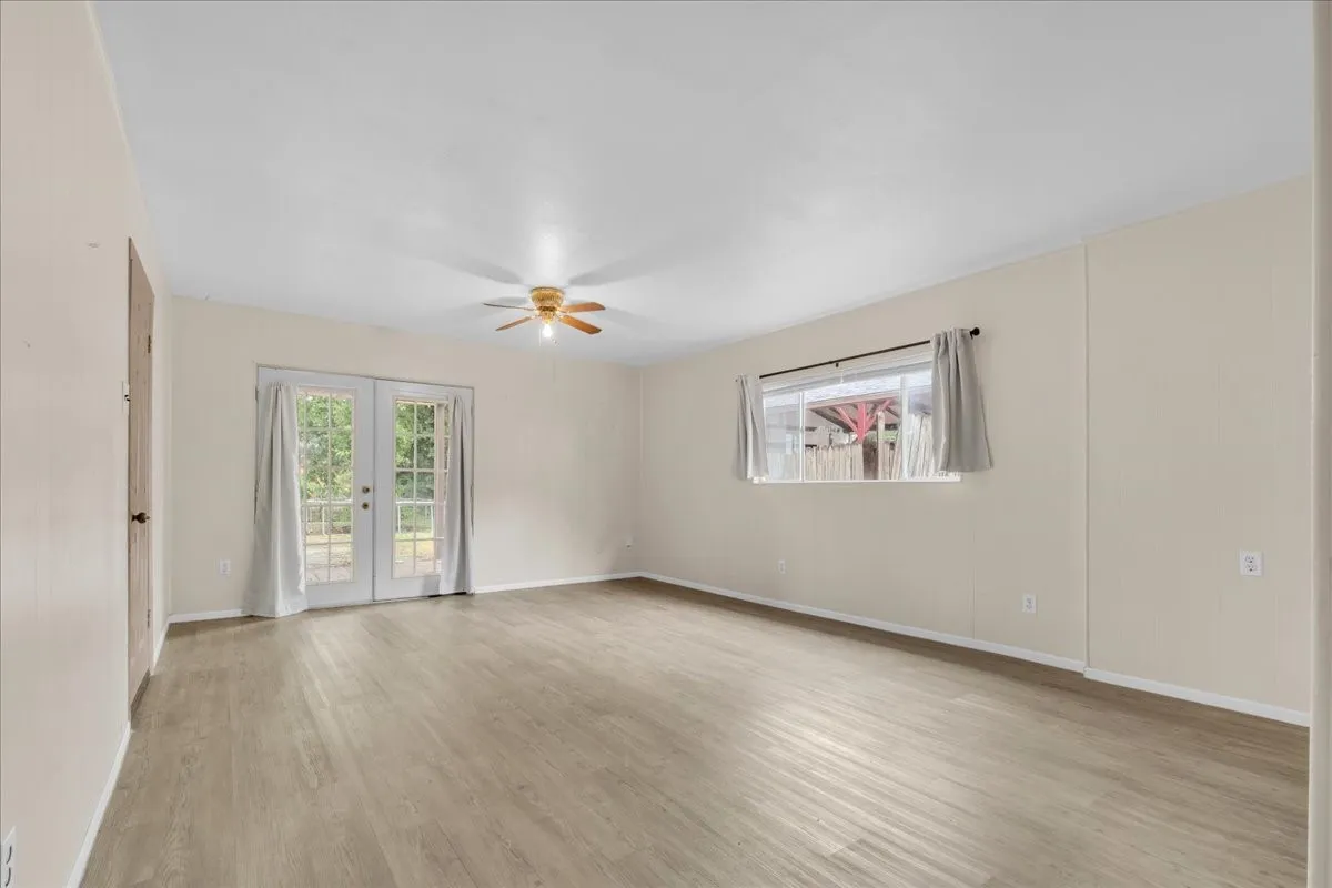Expansive interior space featuring wood-finish flooring, light-toned walls, and a ceiling fan