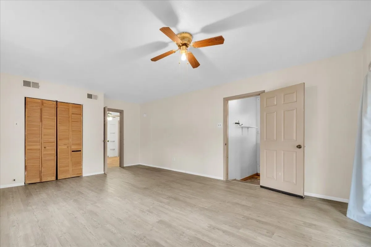 Spacious room featuring wood-finish flooring and a ceiling fan