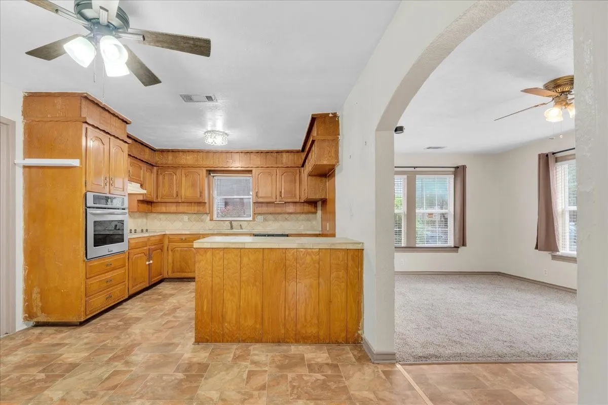 Kitchen featuring wood cabinetry, built-in oven, tile backsplash, and an island with countertop space
