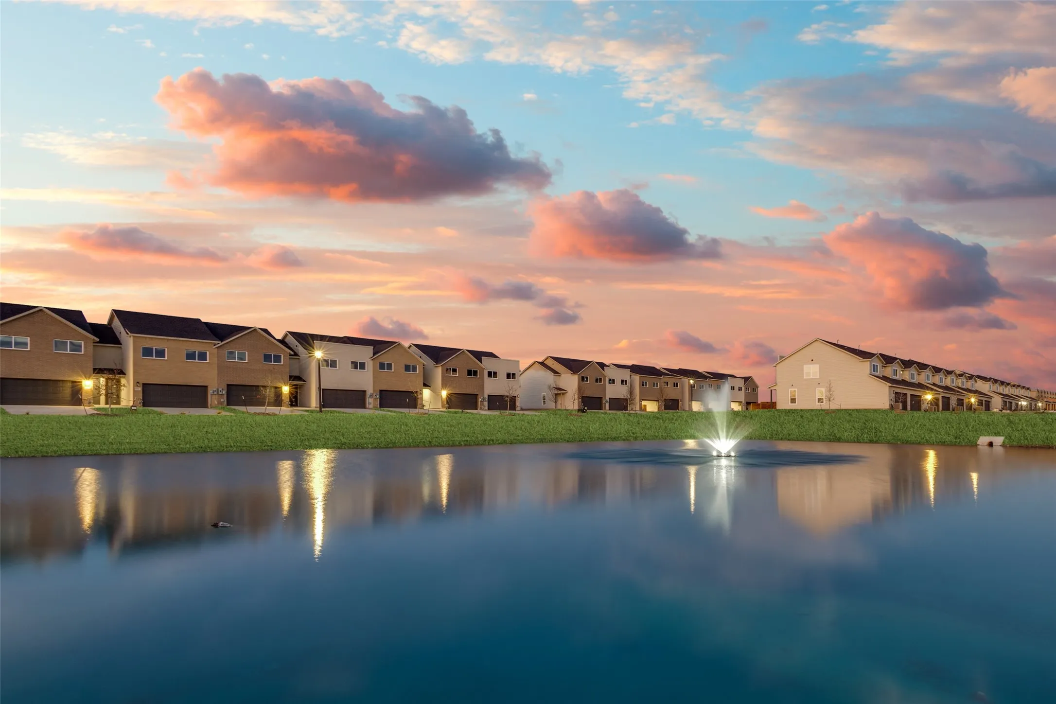 Waterside residences featuring a tranquil pond with an illuminated fountain