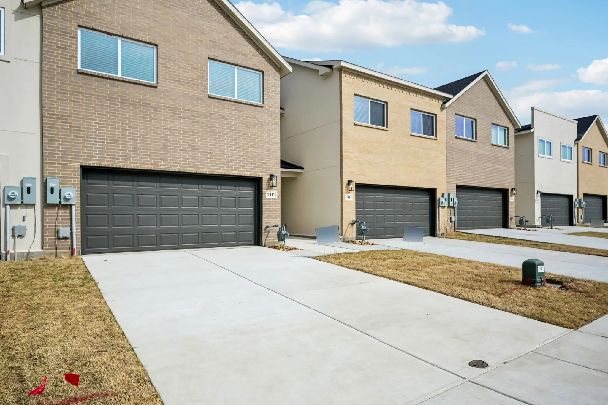 Brick and stucco exterior featuring a two-car garage with a paneled door, concrete driveway, and two upper-level windows
