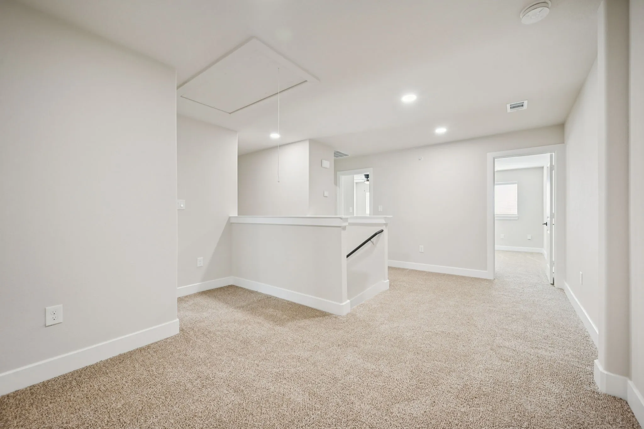 Neutral-toned carpeted loft area featuring recessed lighting, a white balustrade, and light gray wall paint