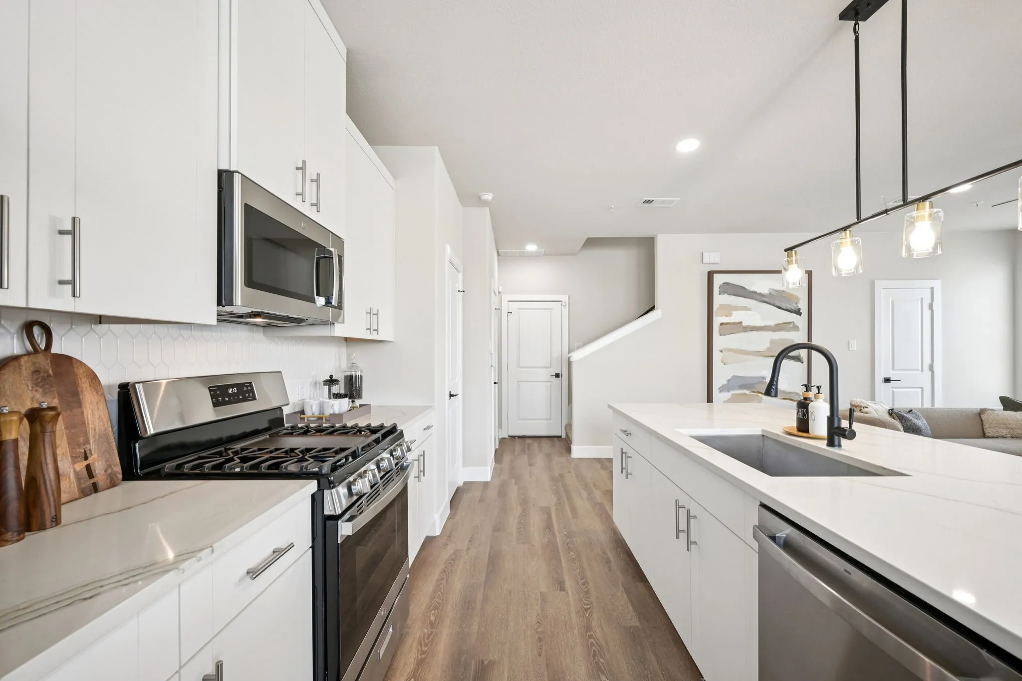 Modern kitchen featuring white cabinetry, stainless steel appliances, a gas range, a white hexagon tile backsplash, and wood-finish flooring