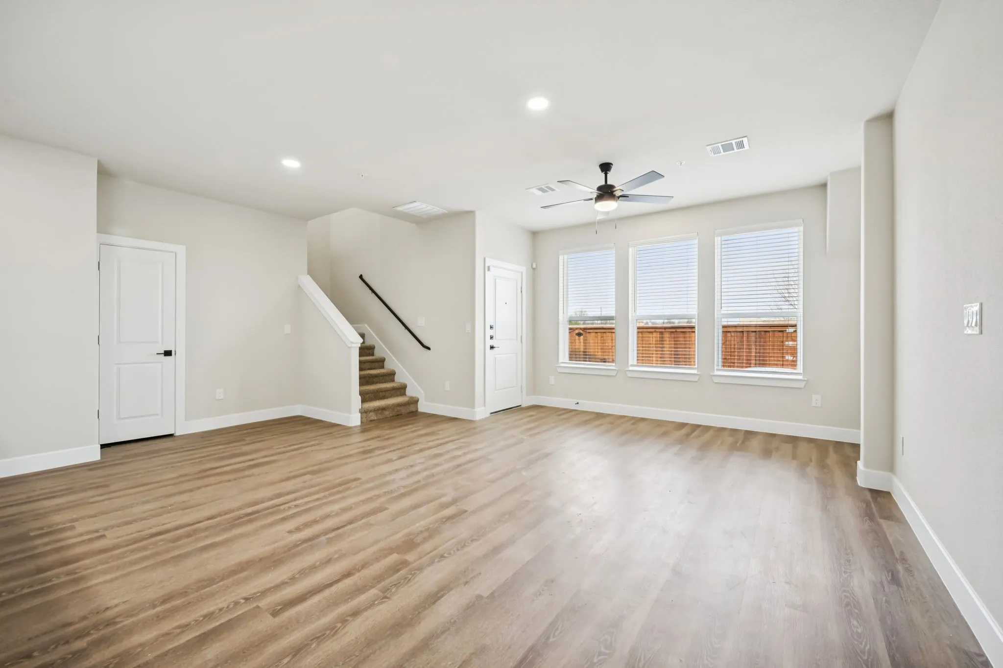Spacious living area featuring wood-finish flooring, a contemporary ceiling fan, and recessed lighting