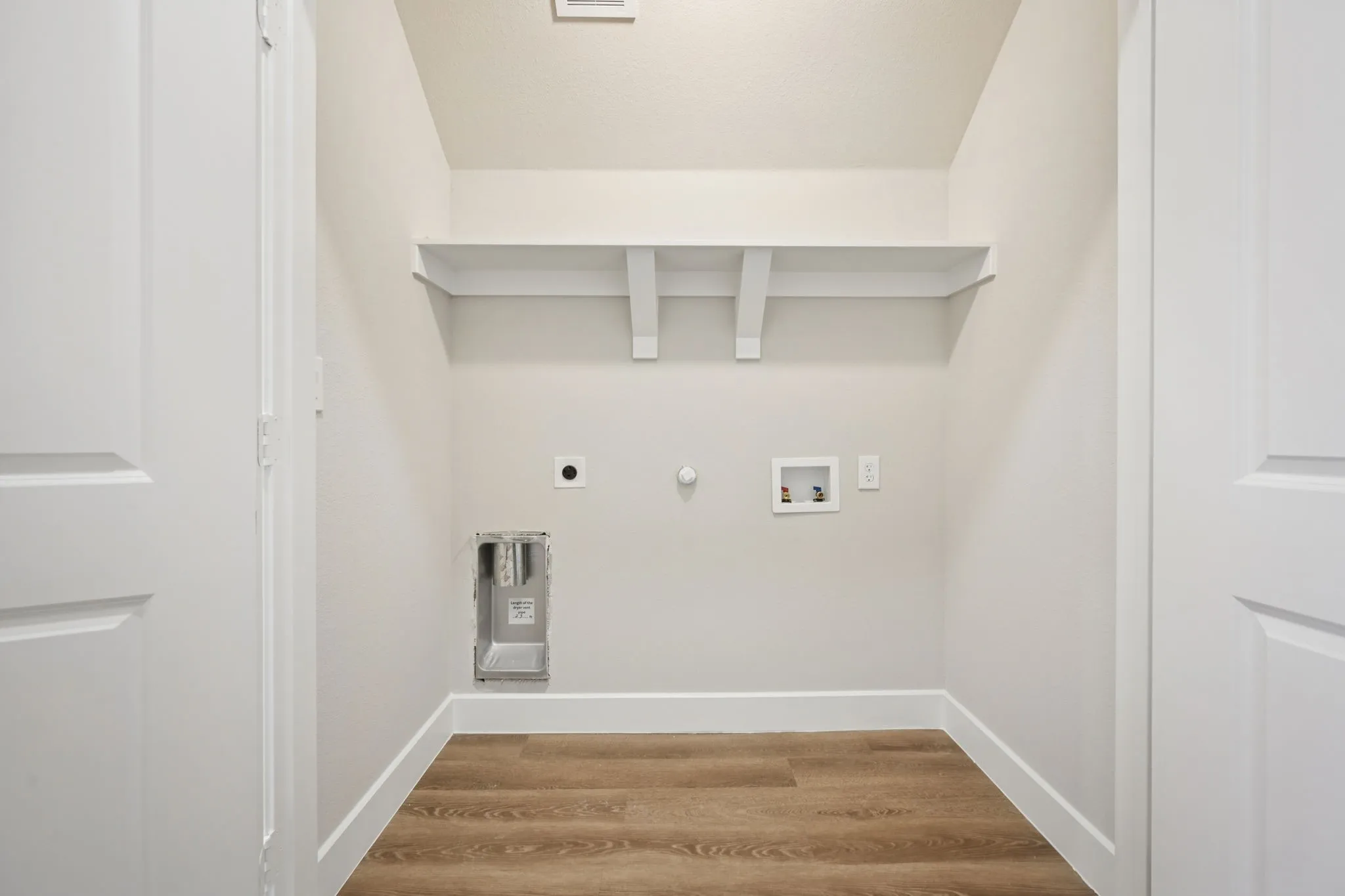 Dedicated utility area featuring wood-finish flooring and a built-in storage shelf