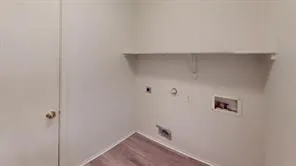 Utility area featuring wood-finish flooring, a wall-mounted shelf, and a white interior door