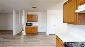 Kitchen area featuring wood-finish flooring, white countertops, and wood cabinetry