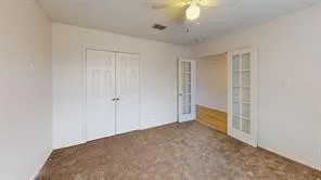 Carpeted interior space featuring white walls and a ceiling fan