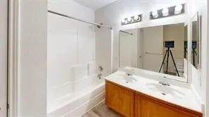 Bathroom featuring a double vanity with integrated sinks, a wood-finish cabinet base, and a full-width mirror