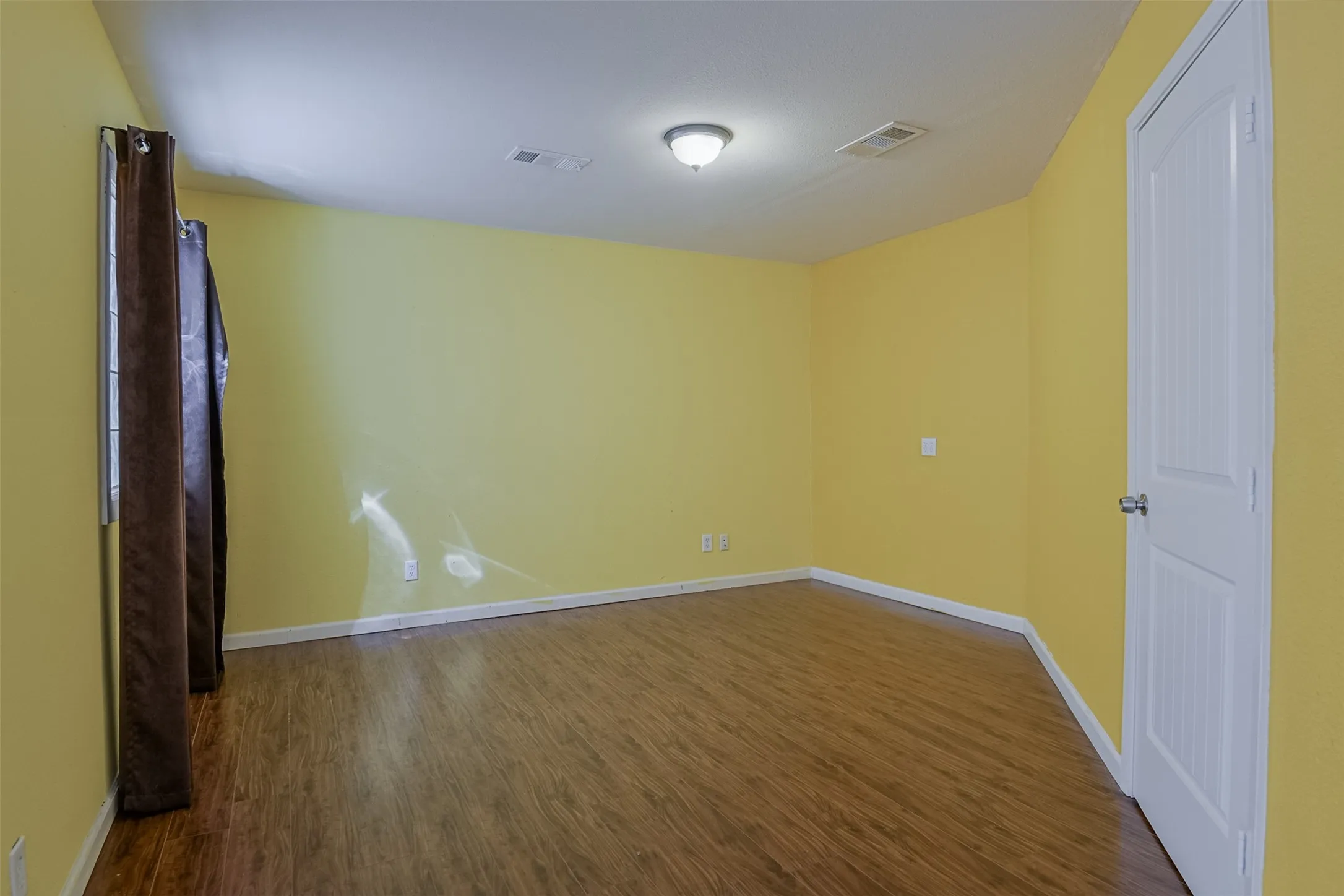 Room featuring wood-finish flooring, white trim, recessed lighting, and a paneled interior door