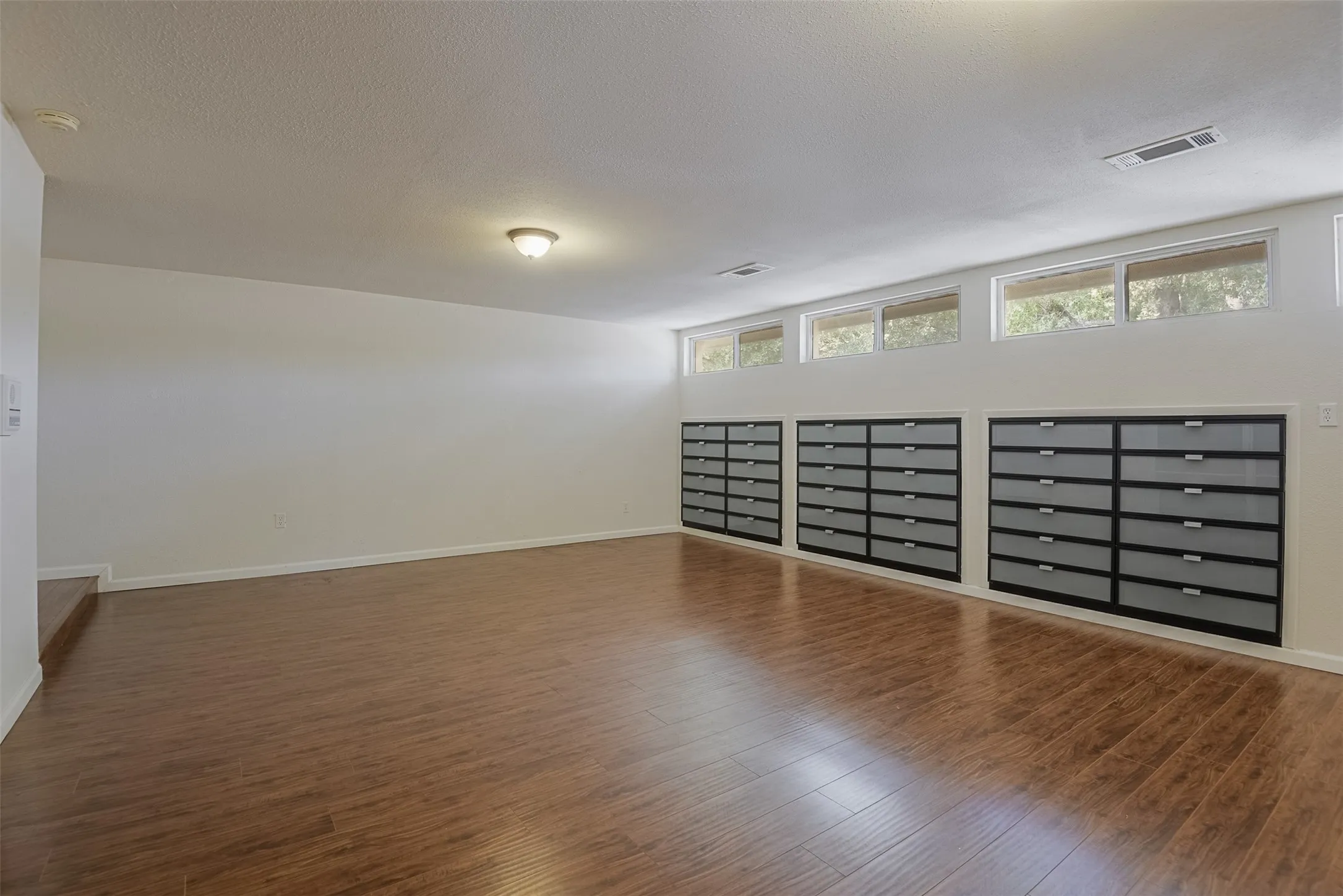 Wood-finish flooring, built-in storage drawers, and upper transom windows
