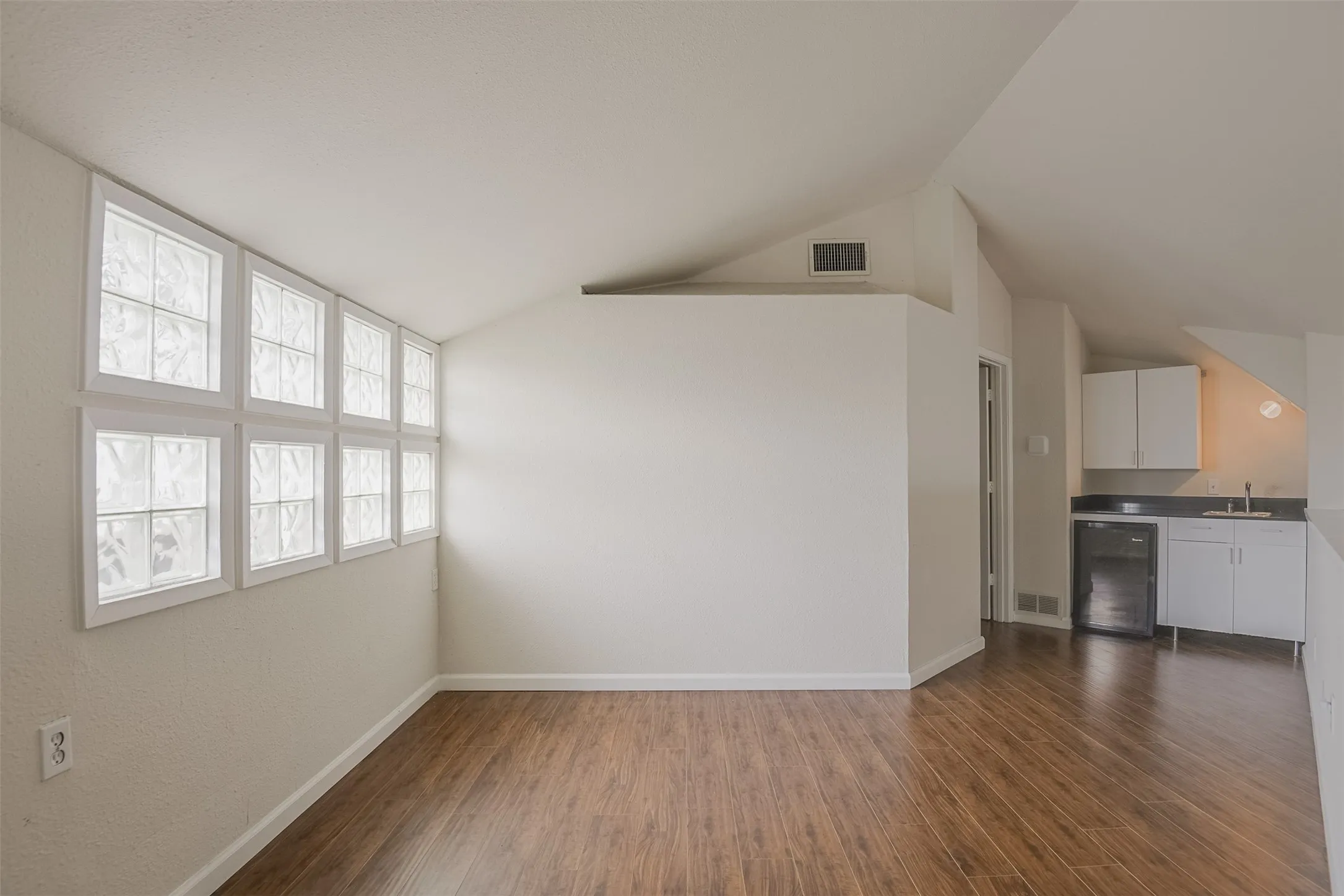 Wood-finish flooring, glass block windows, and a built-in kitchenette with a sink and cabinetry