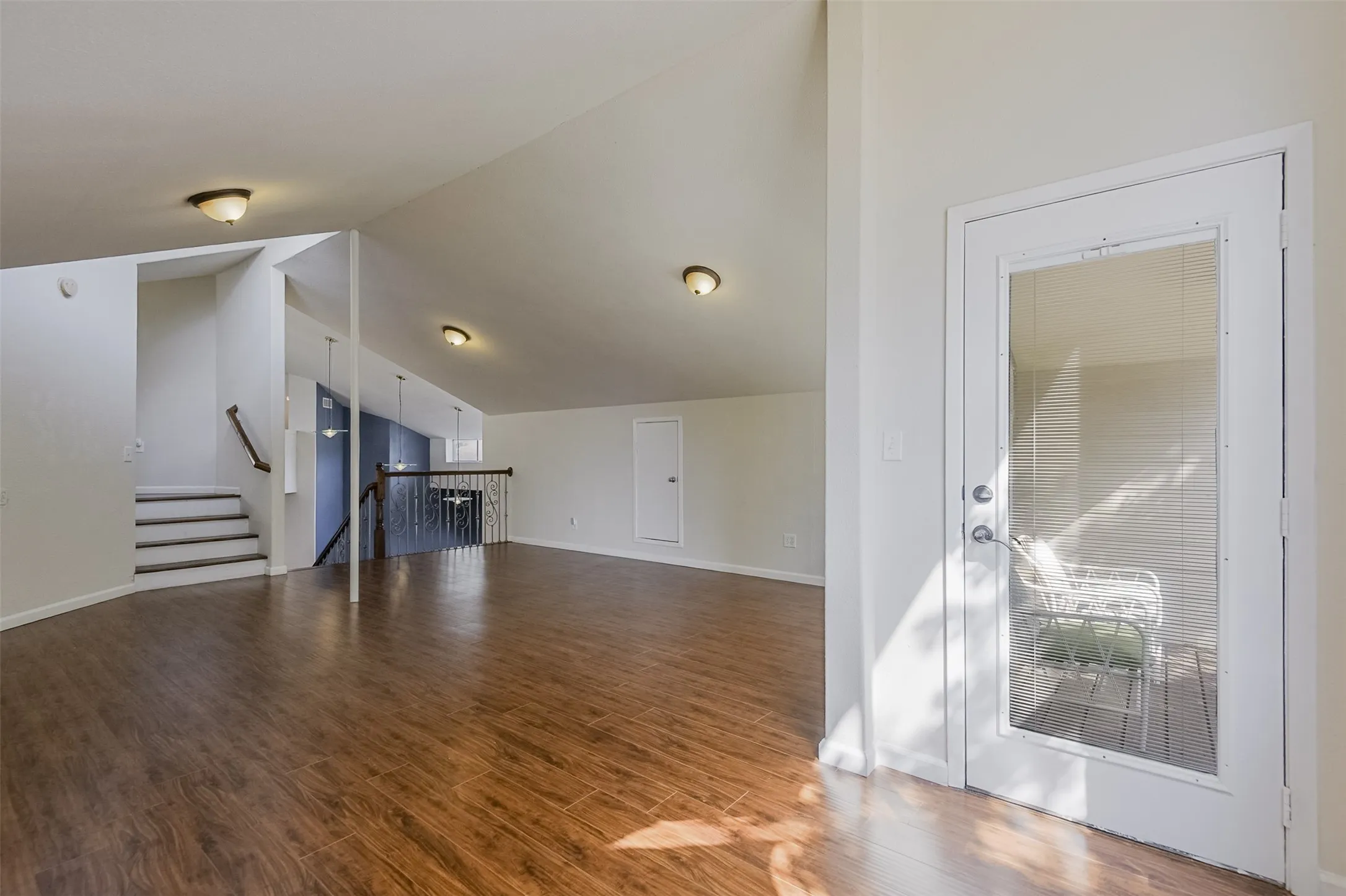 Wood-finish flooring, white walls, and sloped ceilings