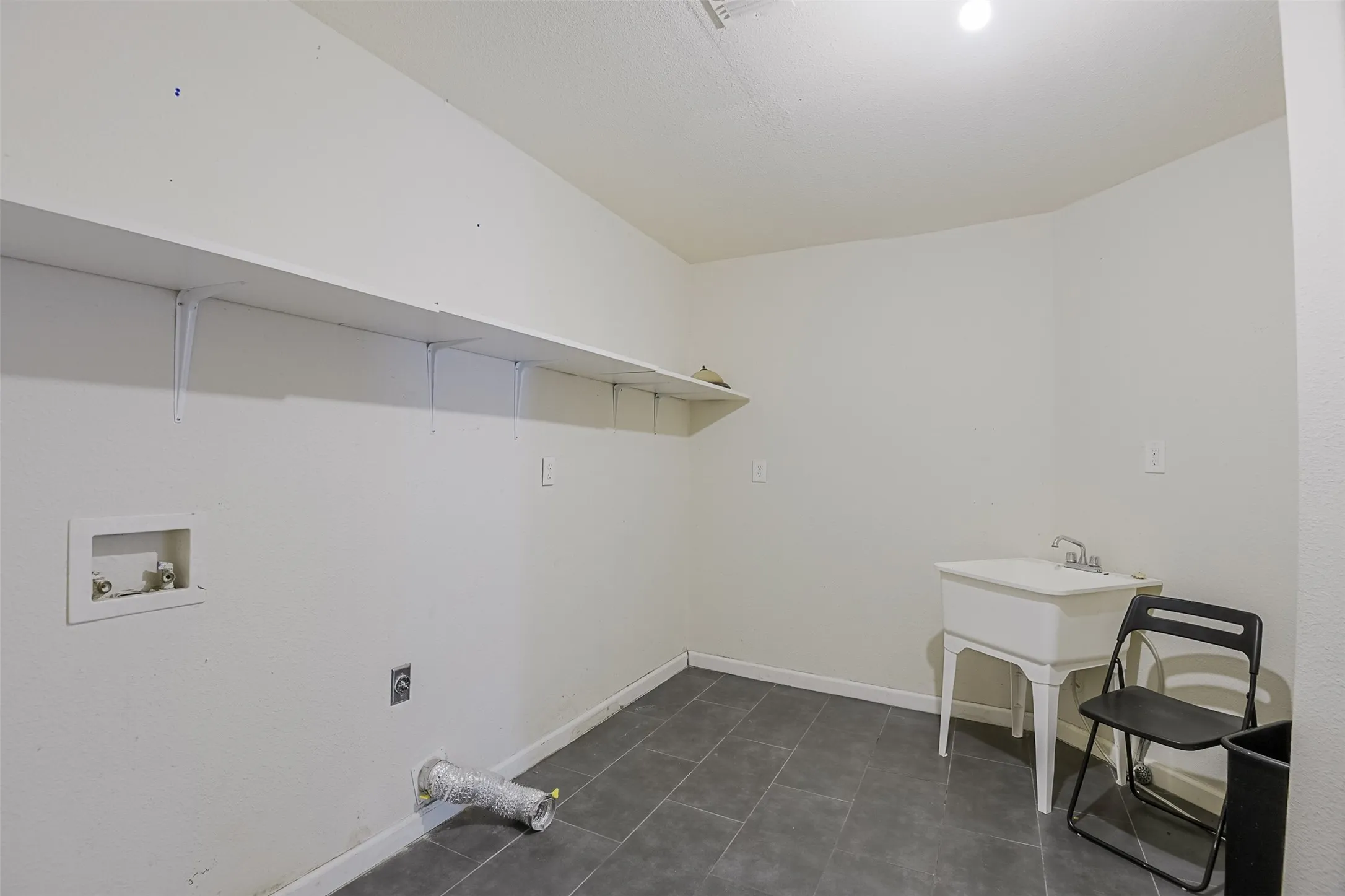 Laundry area featuring tiled flooring, built-in shelving, a utility sink, and appliance hookups