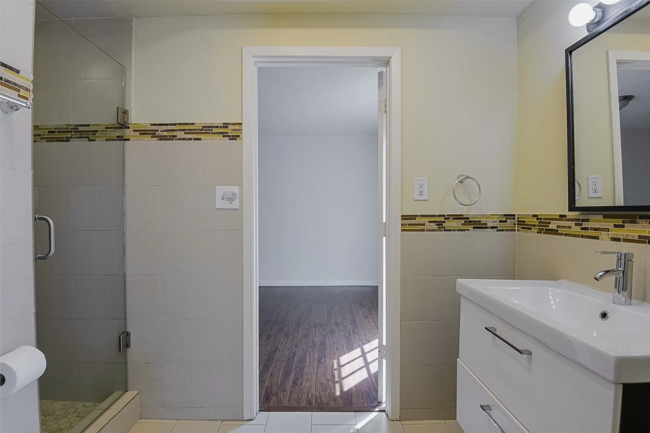 Bathroom featuring a glass-enclosed shower, mosaic tile accent, vanity with integrated sink, and modern faucet