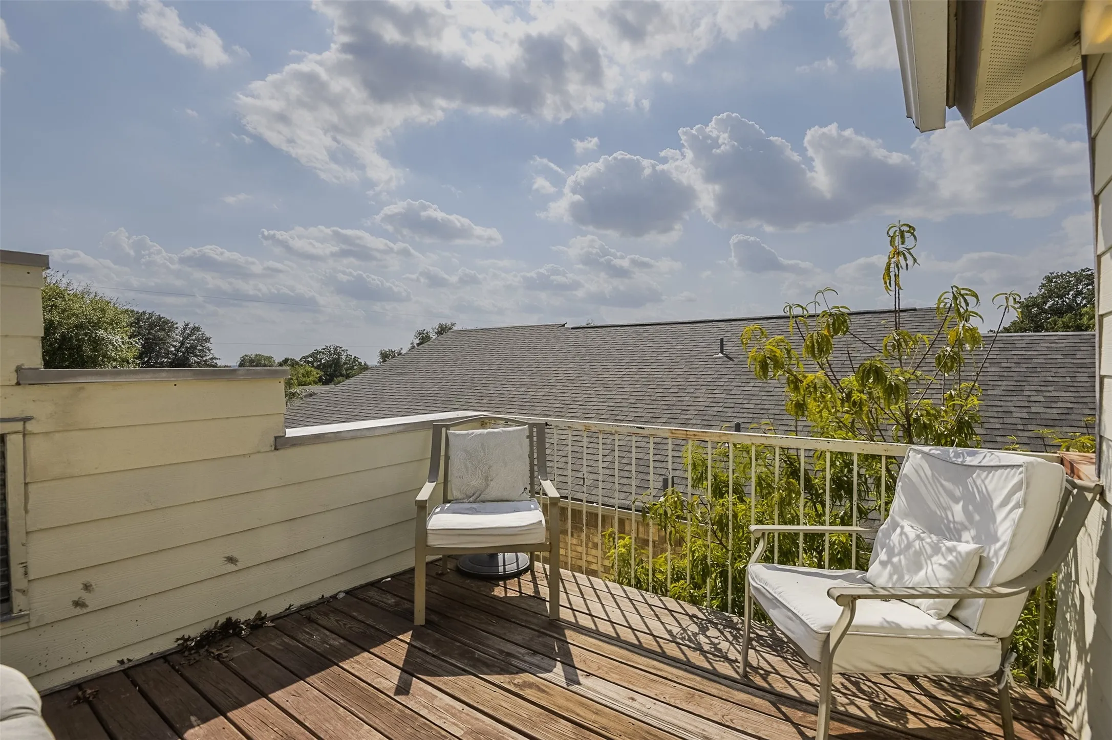Wood-finish decking with a white metal railing and a visible roofline