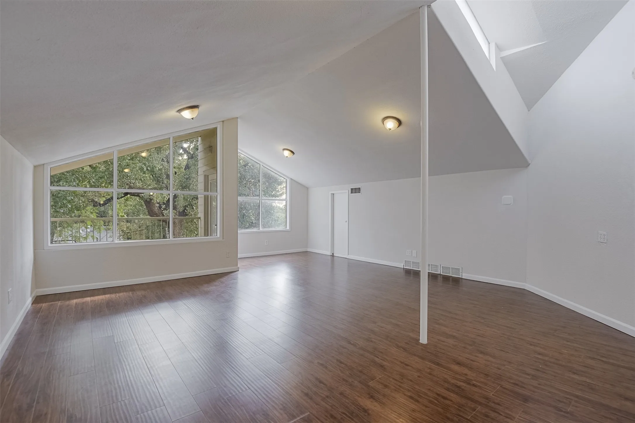 Wood-finish flooring, vaulted ceilings, sloped architectural windows, skylight, and white interior doors