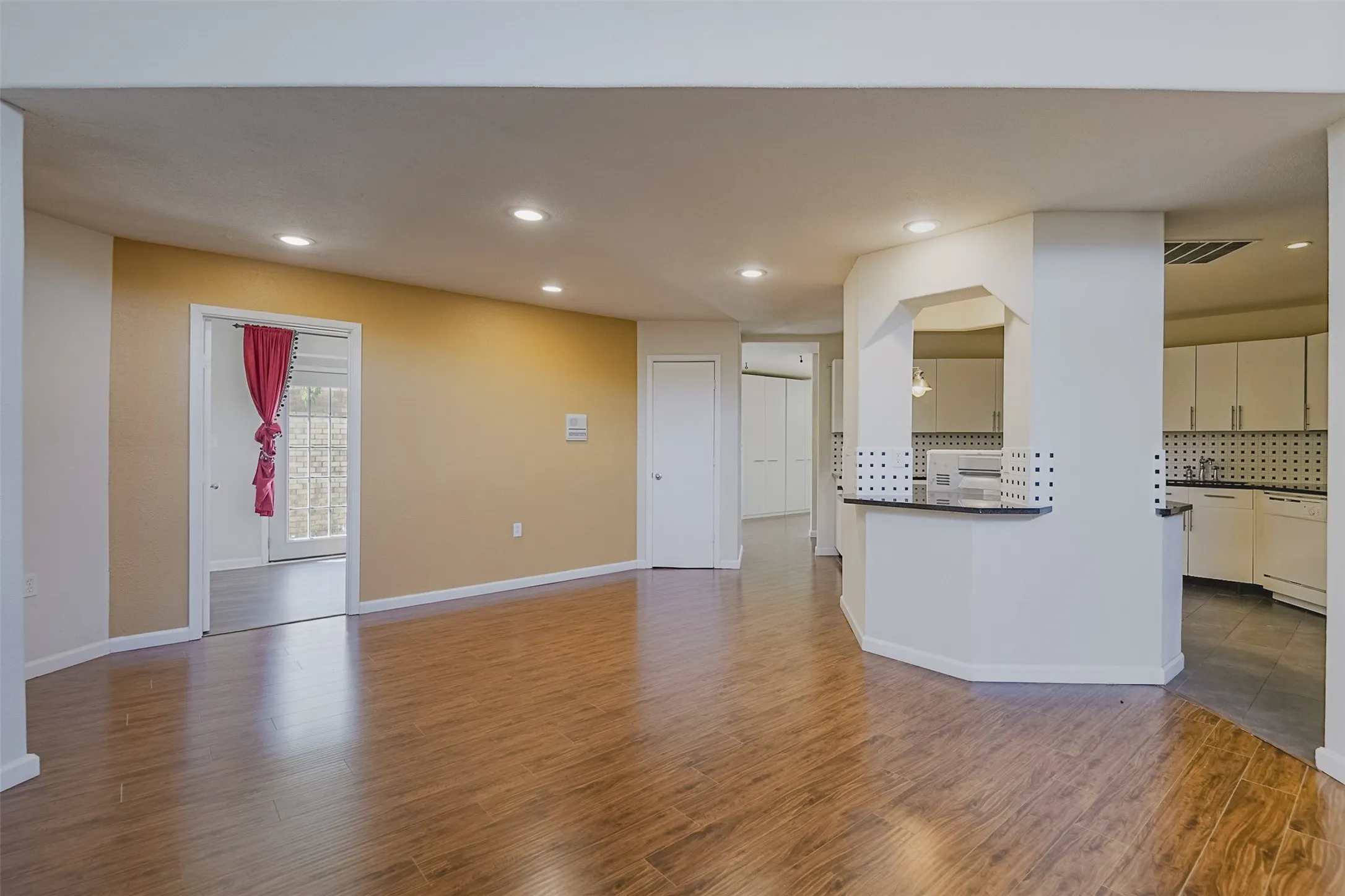 Wood-finish flooring, recessed lighting, and a kitchen pass-through with a breakfast bar
