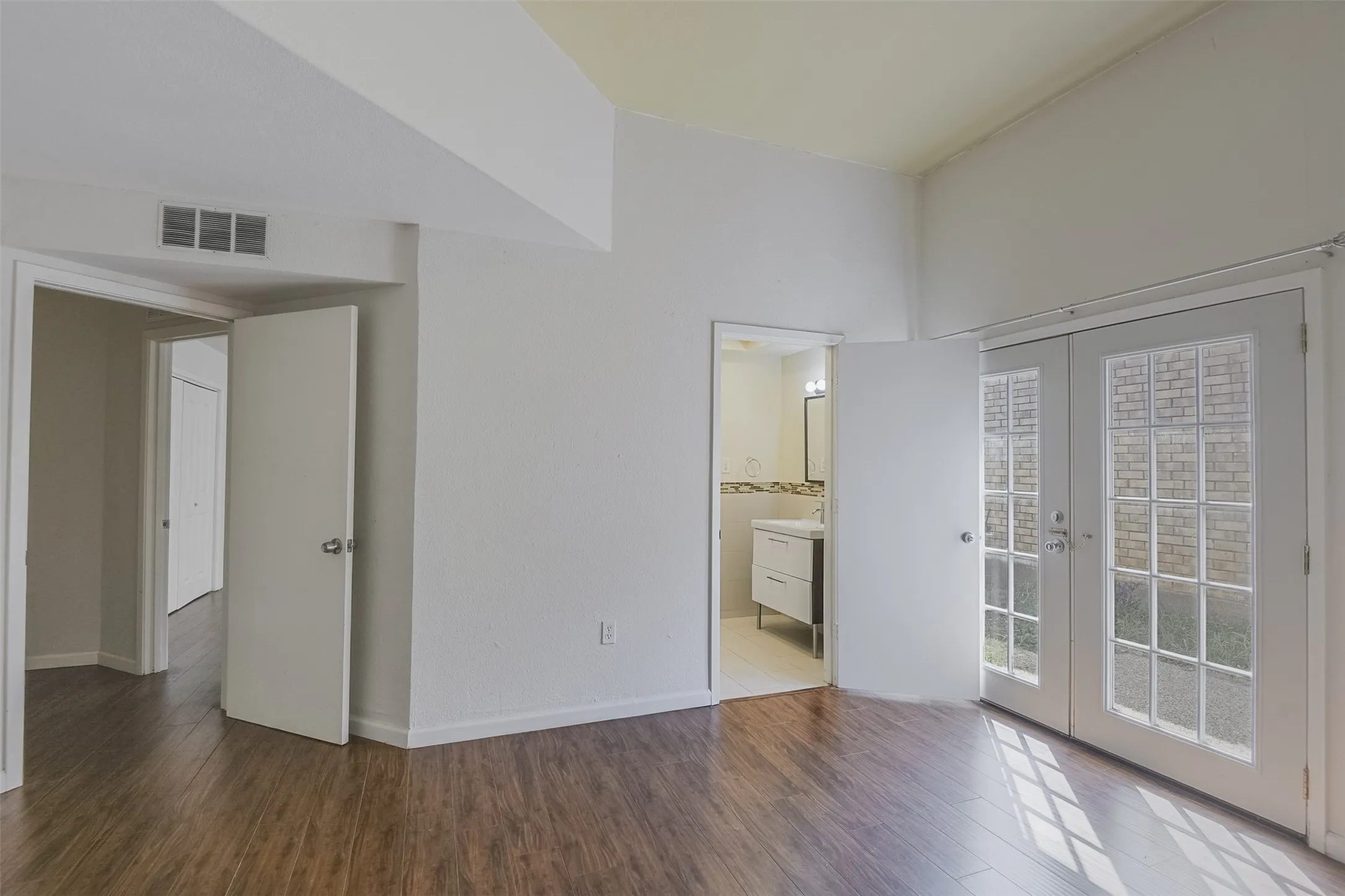 Wood-finish flooring throughout, vaulted ceilings, and white paneled doors