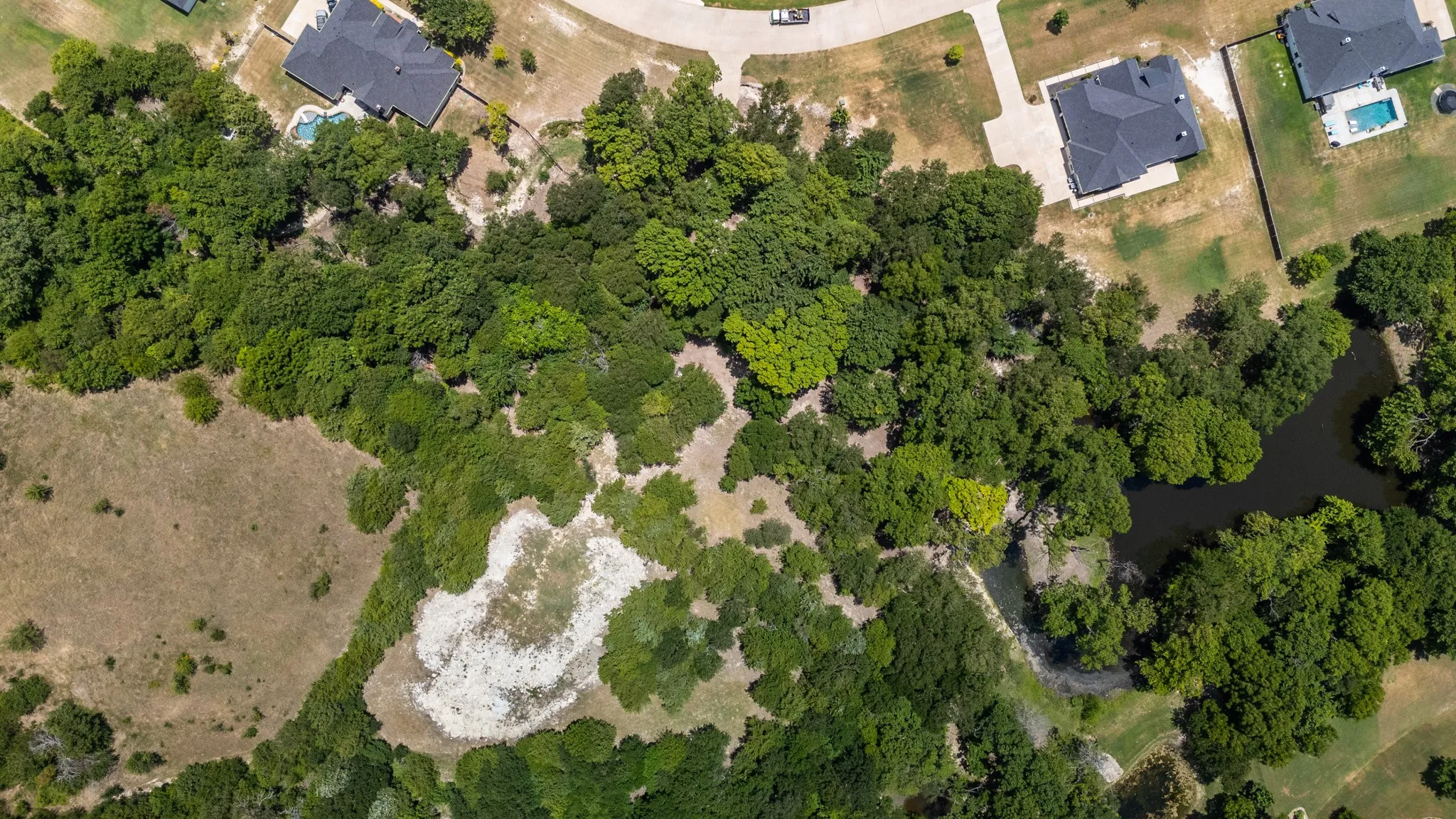 Expansive lot featuring a natural tree line and a distinct water feature