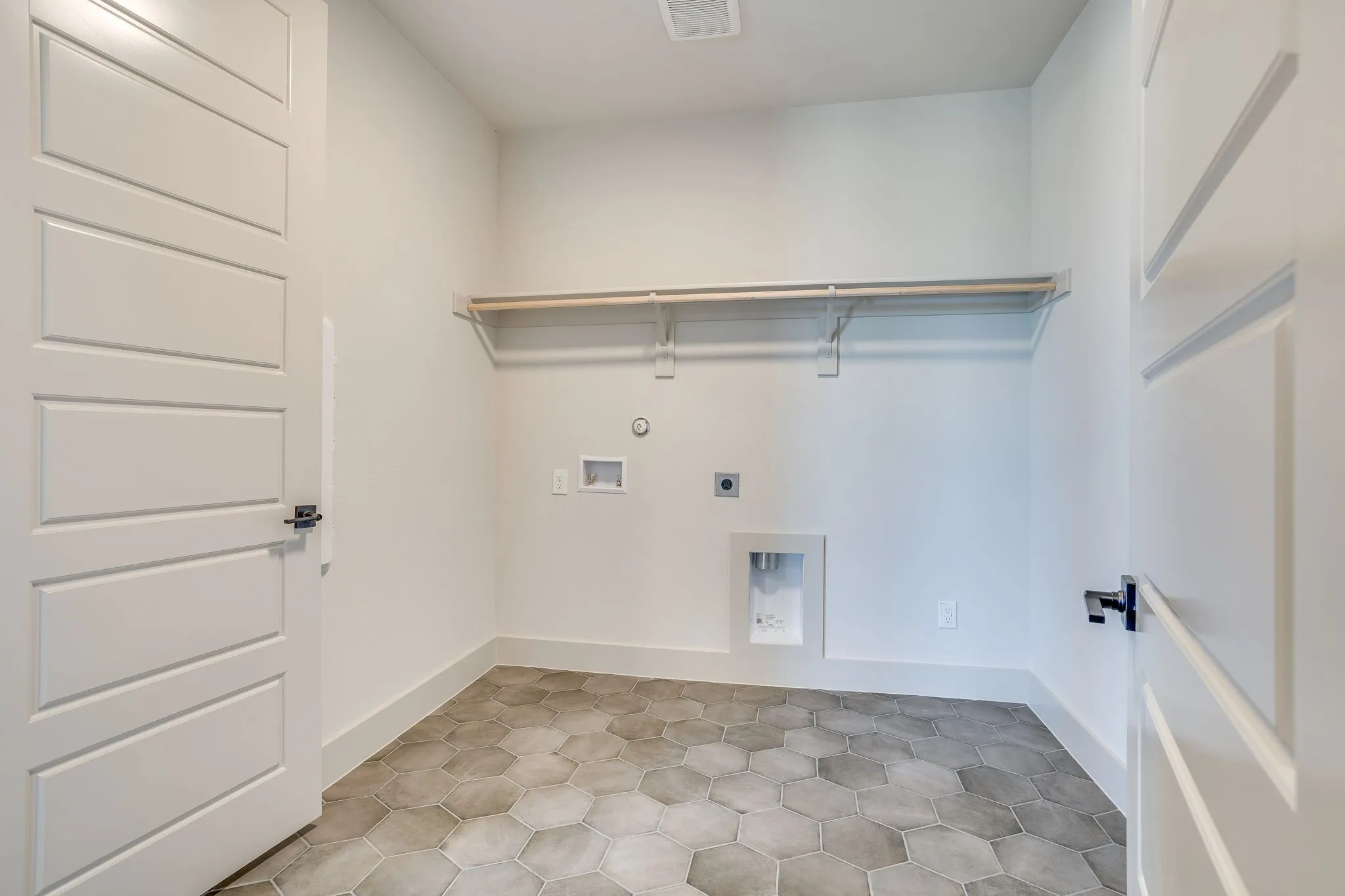 Laundry room featuring hexagonal floor tiles, white walls, and a built-in hanging rod