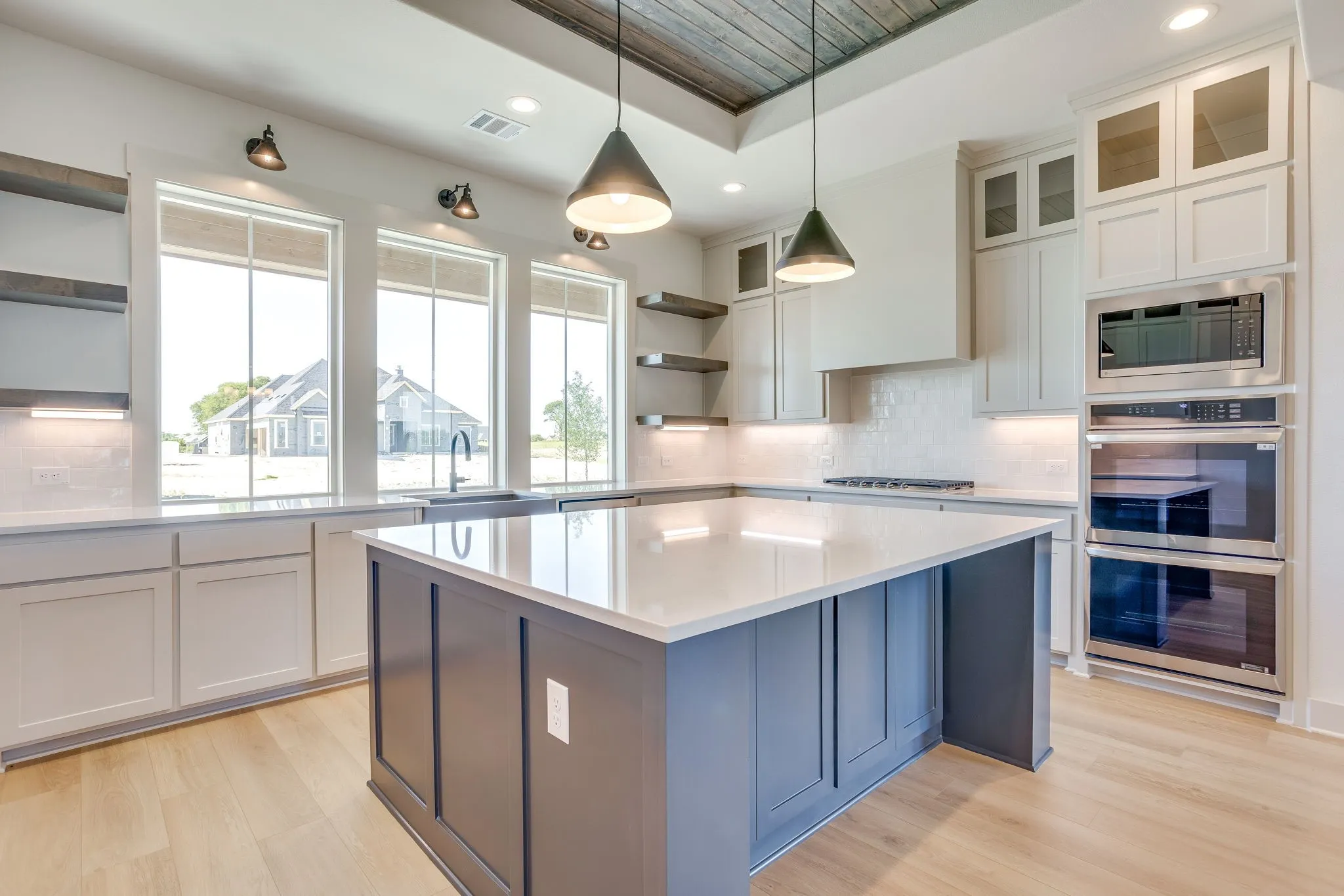 Kitchen featuring a large island with white quartz countertops, stainless steel appliances, wood-finish flooring, white cabinetry, and recessed lighting