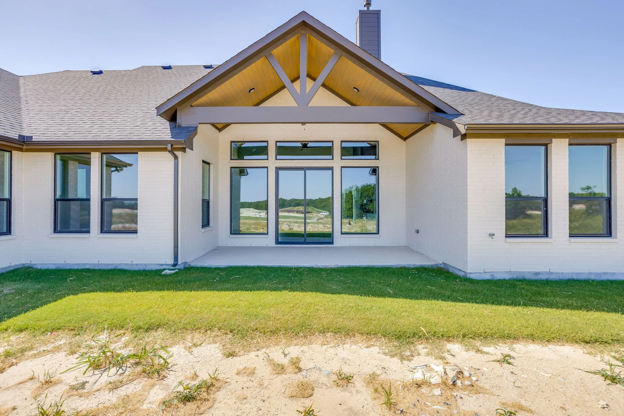 Exterior featuring a covered patio with a vaulted wood-finish ceiling, exposed beams, and a concrete slab