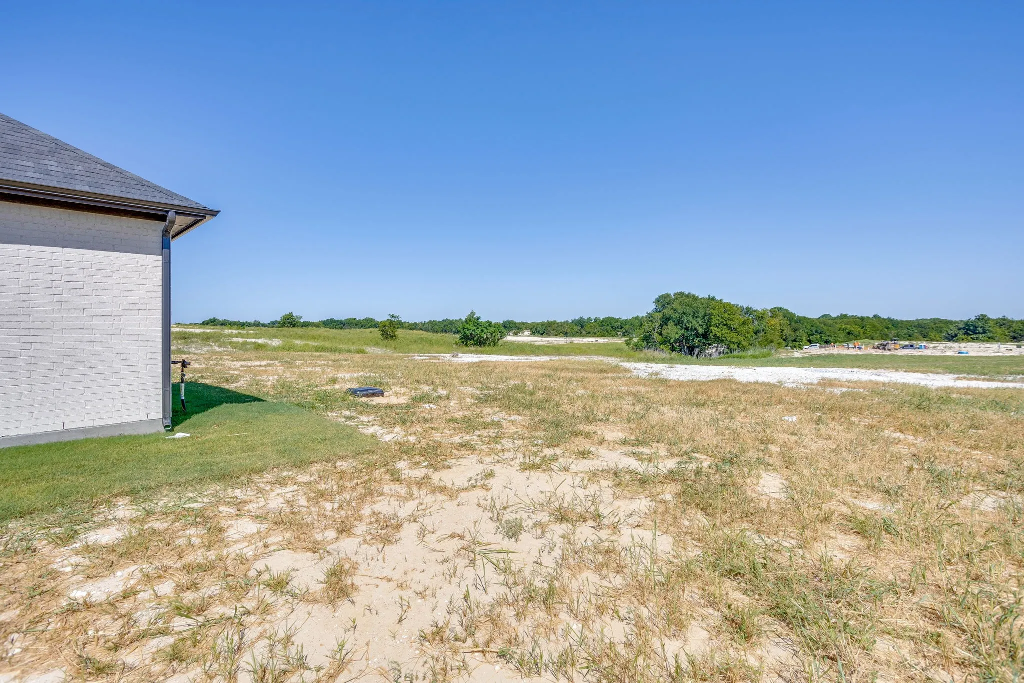 Expansive undeveloped lot featuring a partially graded landscape with natural vegetation and distant trees