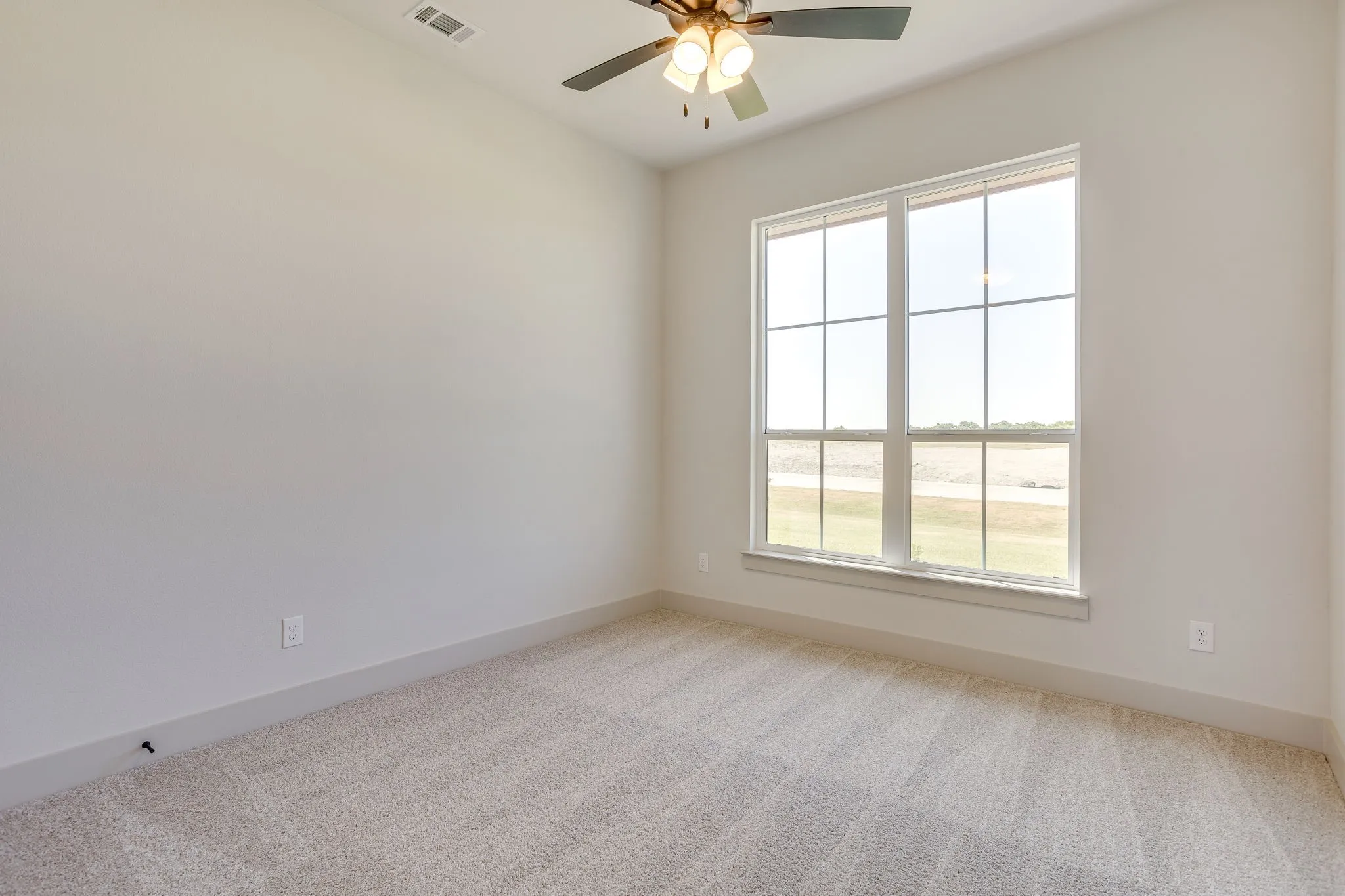 Bright room featuring a large multi-pane window, neutral-toned walls, and plush carpeting