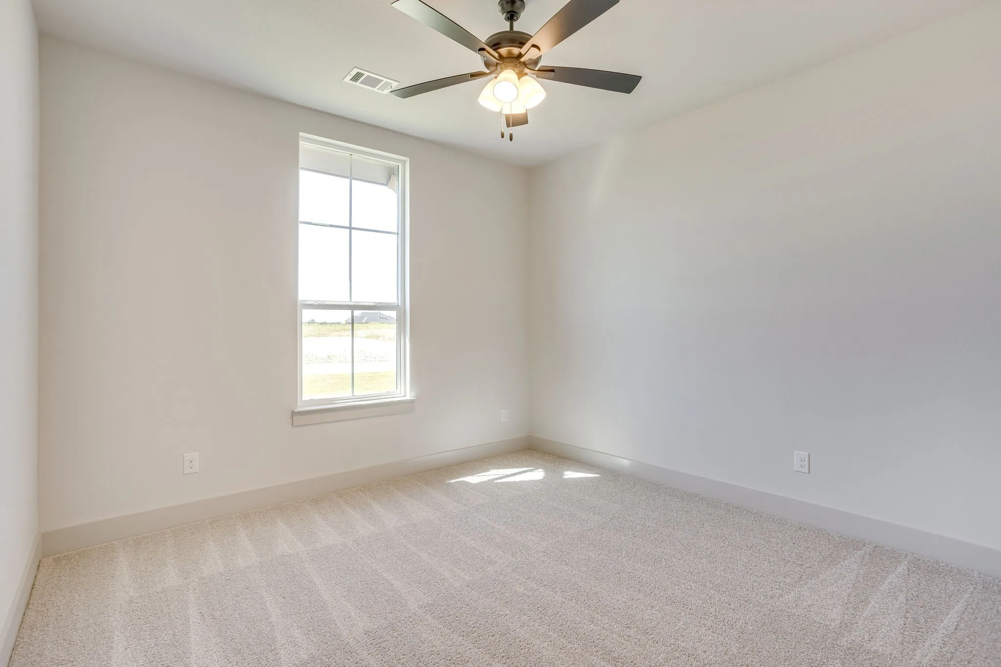 Carpeted room featuring a ceiling fan with light fixture, a window with grid panes, and neutral wall tones