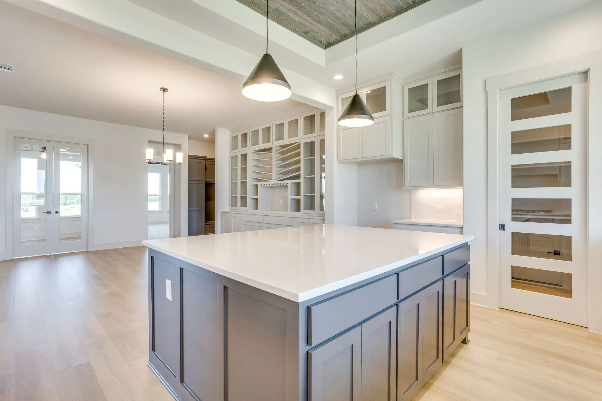 Kitchen island with a light-toned countertop, gray cabinetry, and pendant lighting