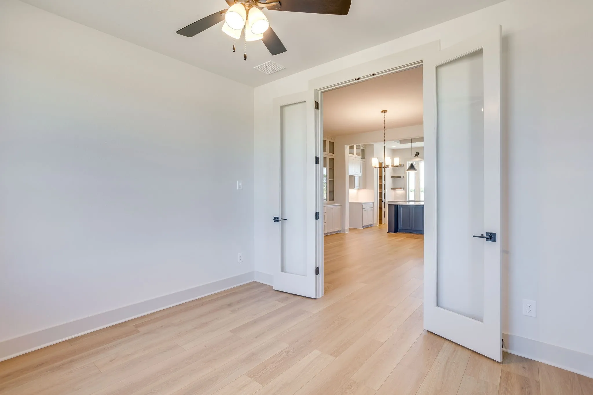 Room with light wood-finish flooring and a ceiling fan