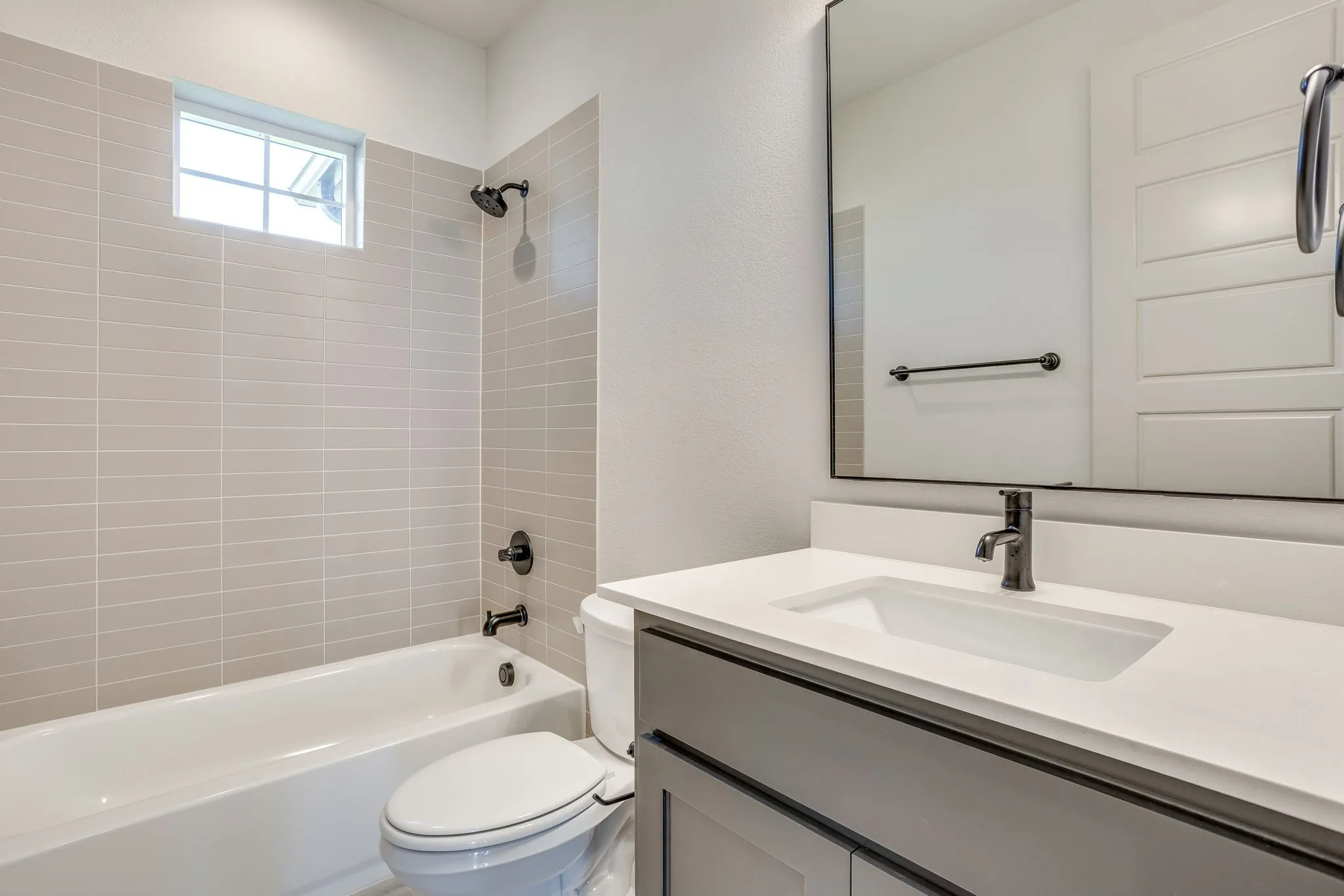 Bathroom featuring a white bathtub, light-toned horizontal tile surround, and black fixtures