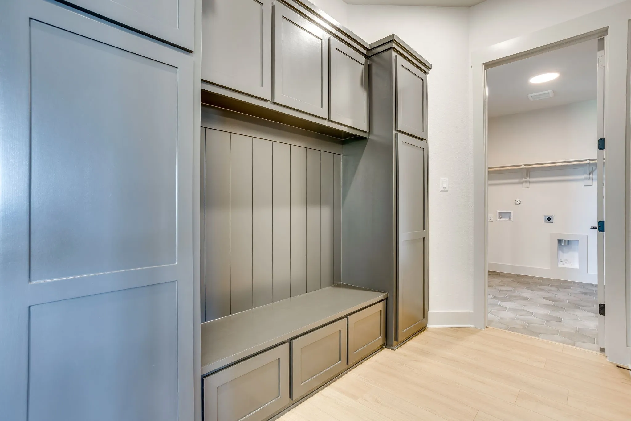 Built-in gray cabinetry featuring upper storage and lower bench seating with integrated drawers