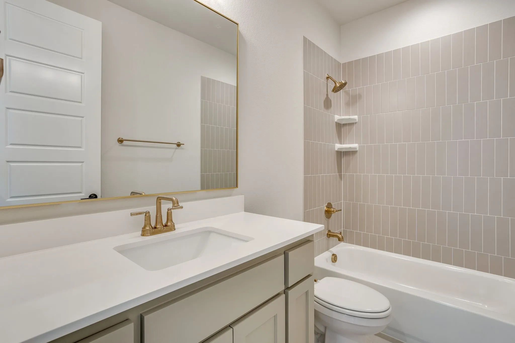 Bathroom featuring a vanity with an undermount sink, a large mirror, and gold-finish fixtures