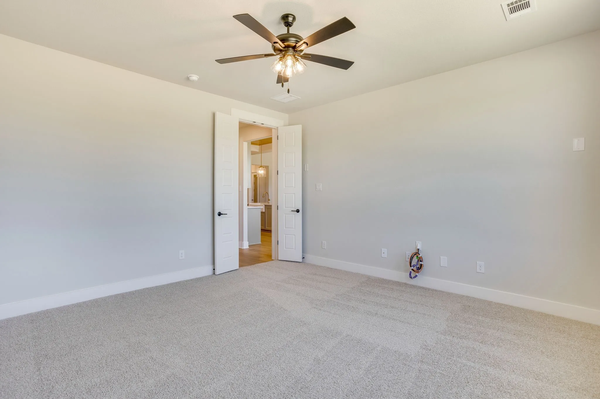 Carpeted room with a ceiling fan featuring a light kit and wood-look blades