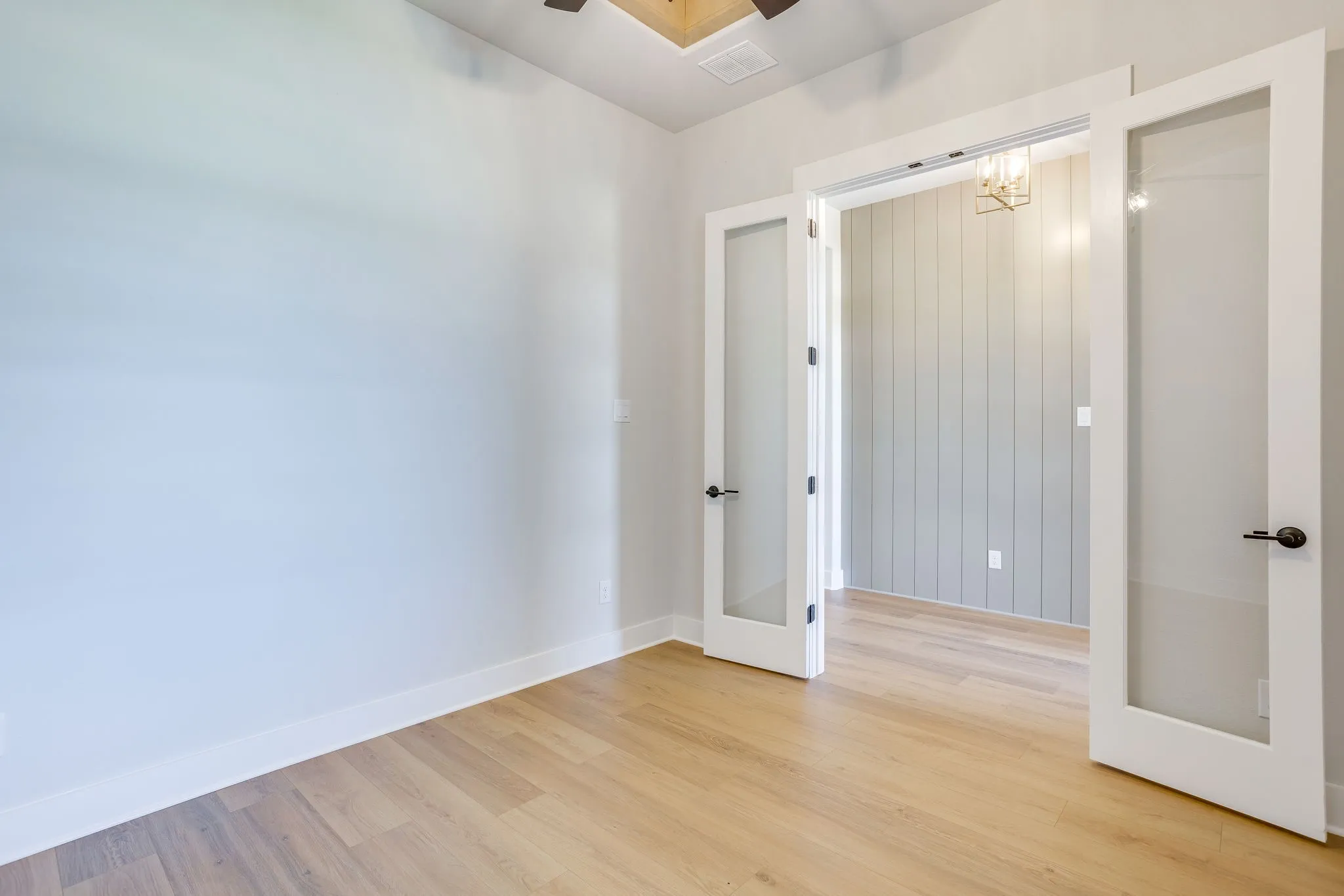 Interior room featuring light-toned wood-finish flooring, white baseboards, and neutral wall paint