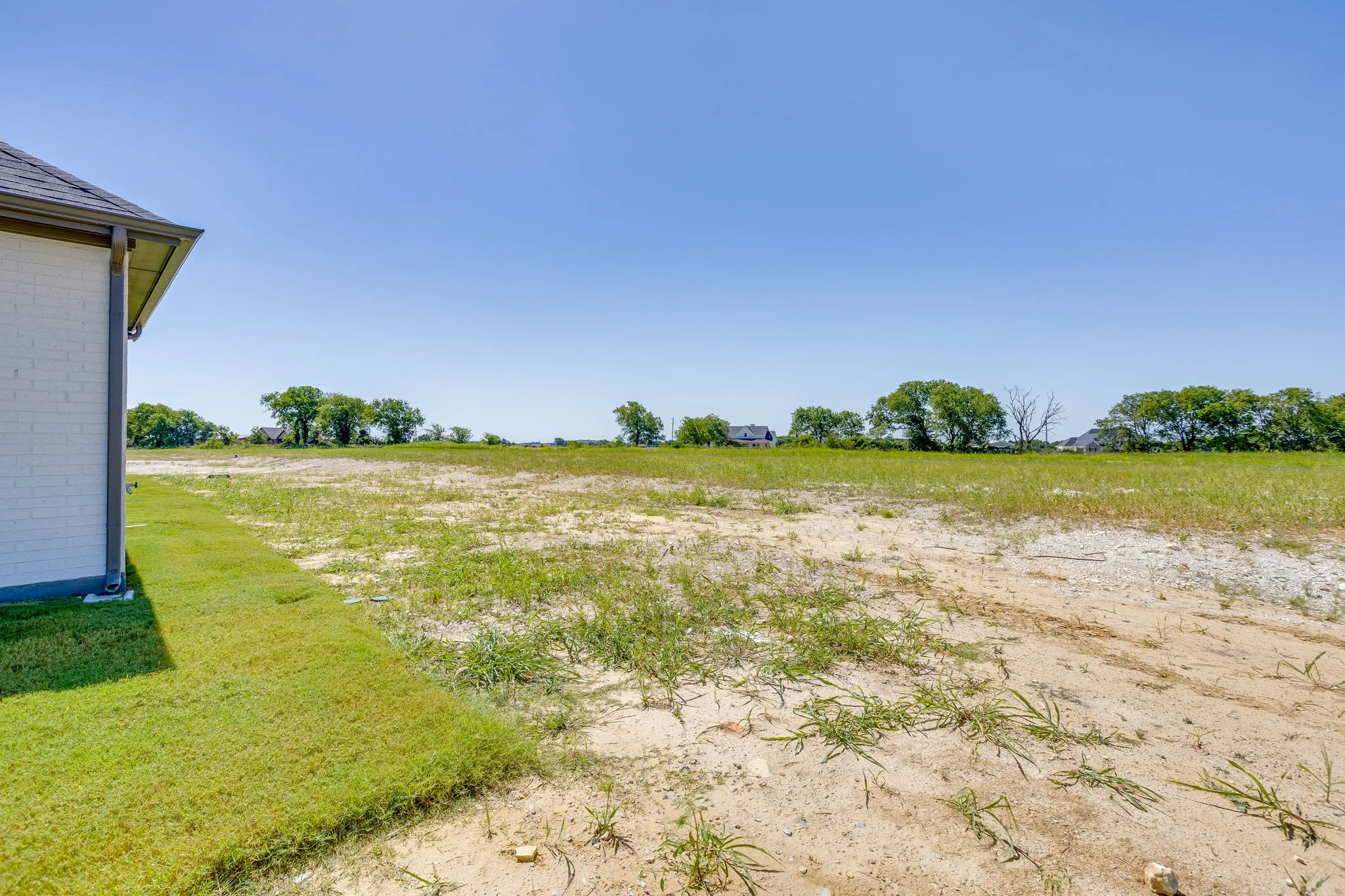 Open land parcel with partial exterior siding and a clear sky backdrop