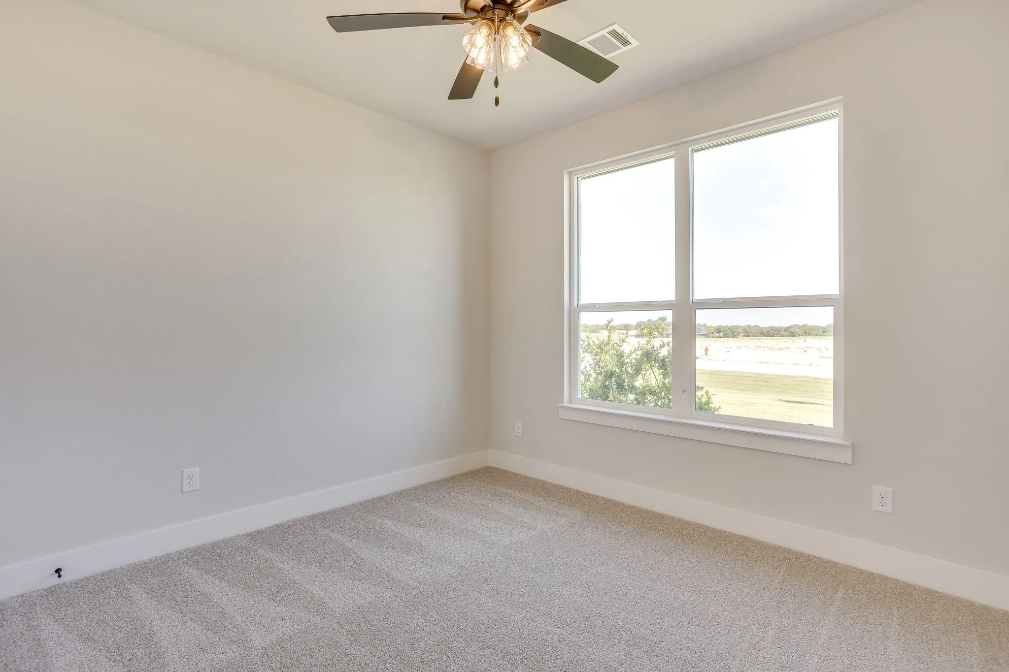 Room featuring light-toned walls, a large window with white trim, and neutral-toned carpeting