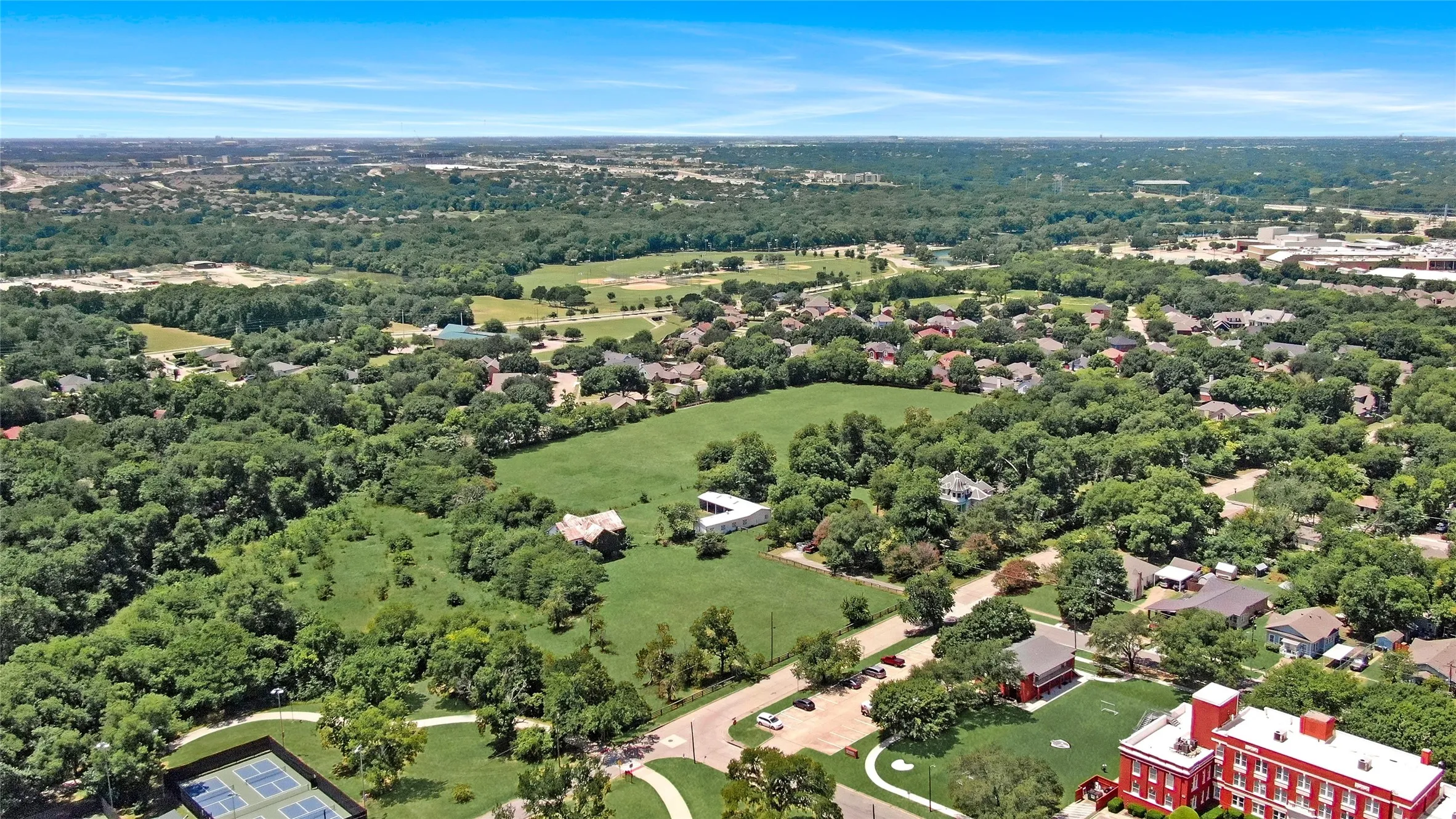 Expansive aerial view showcasing a verdant landscape with extensive tree coverage and open green spaces